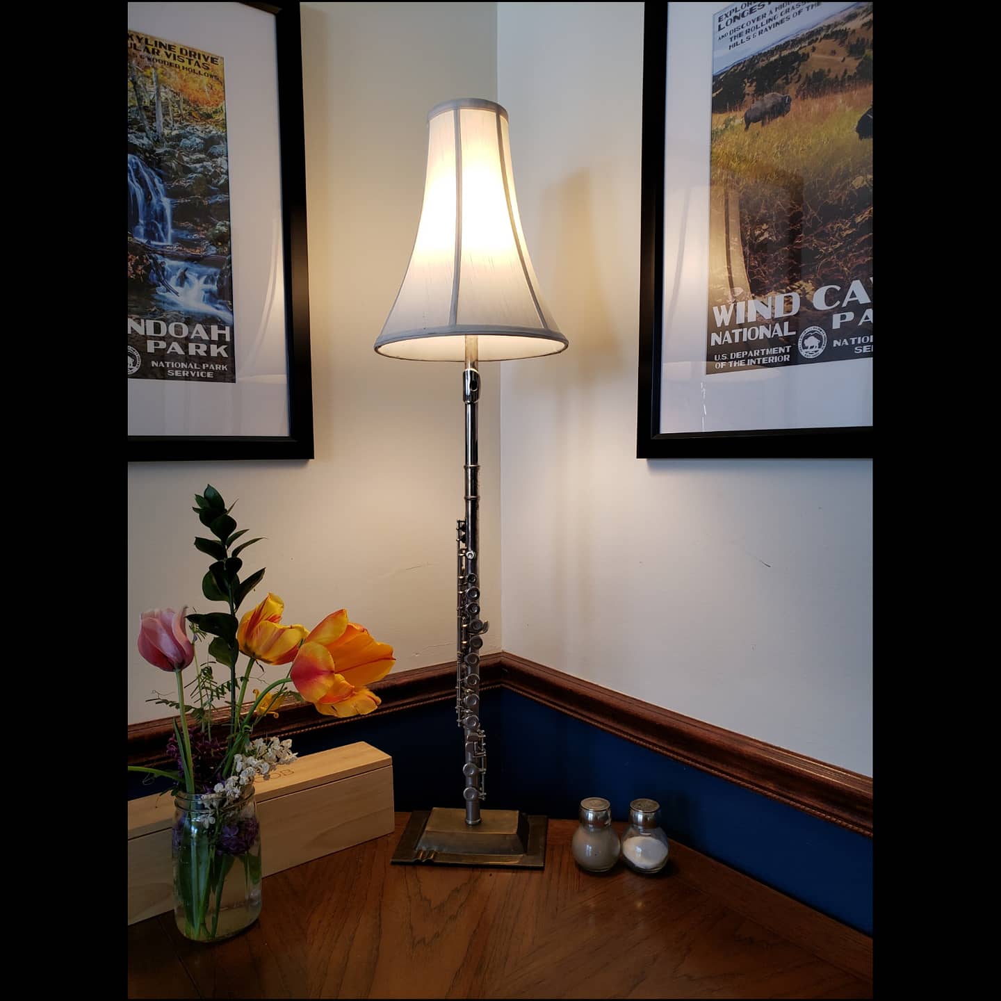 Lamp made from a beginner’s flute and an upside-down brass ashtray base from India, creating elegant tabletop lighting.