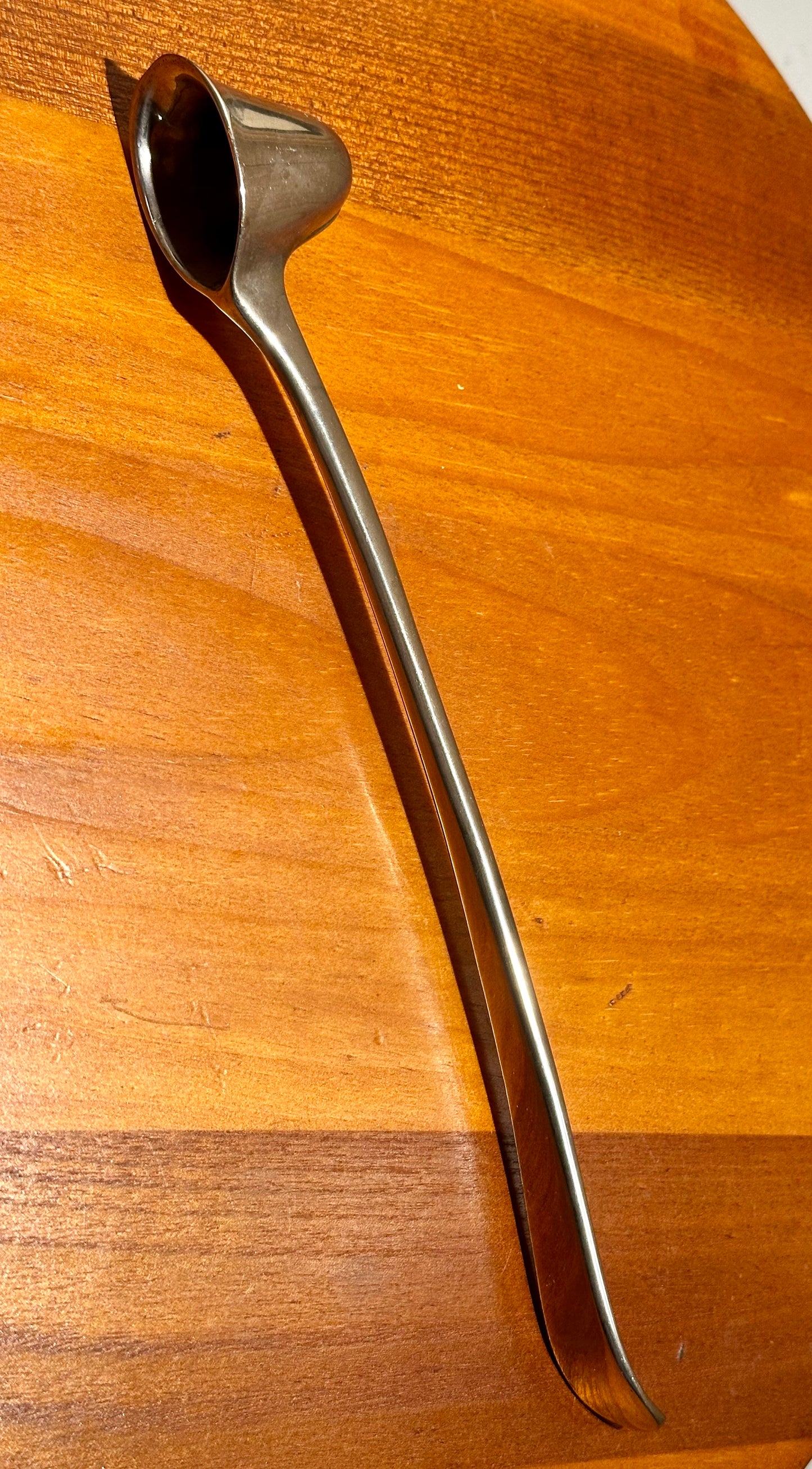 Metallic candle snuffer on a wooden surface