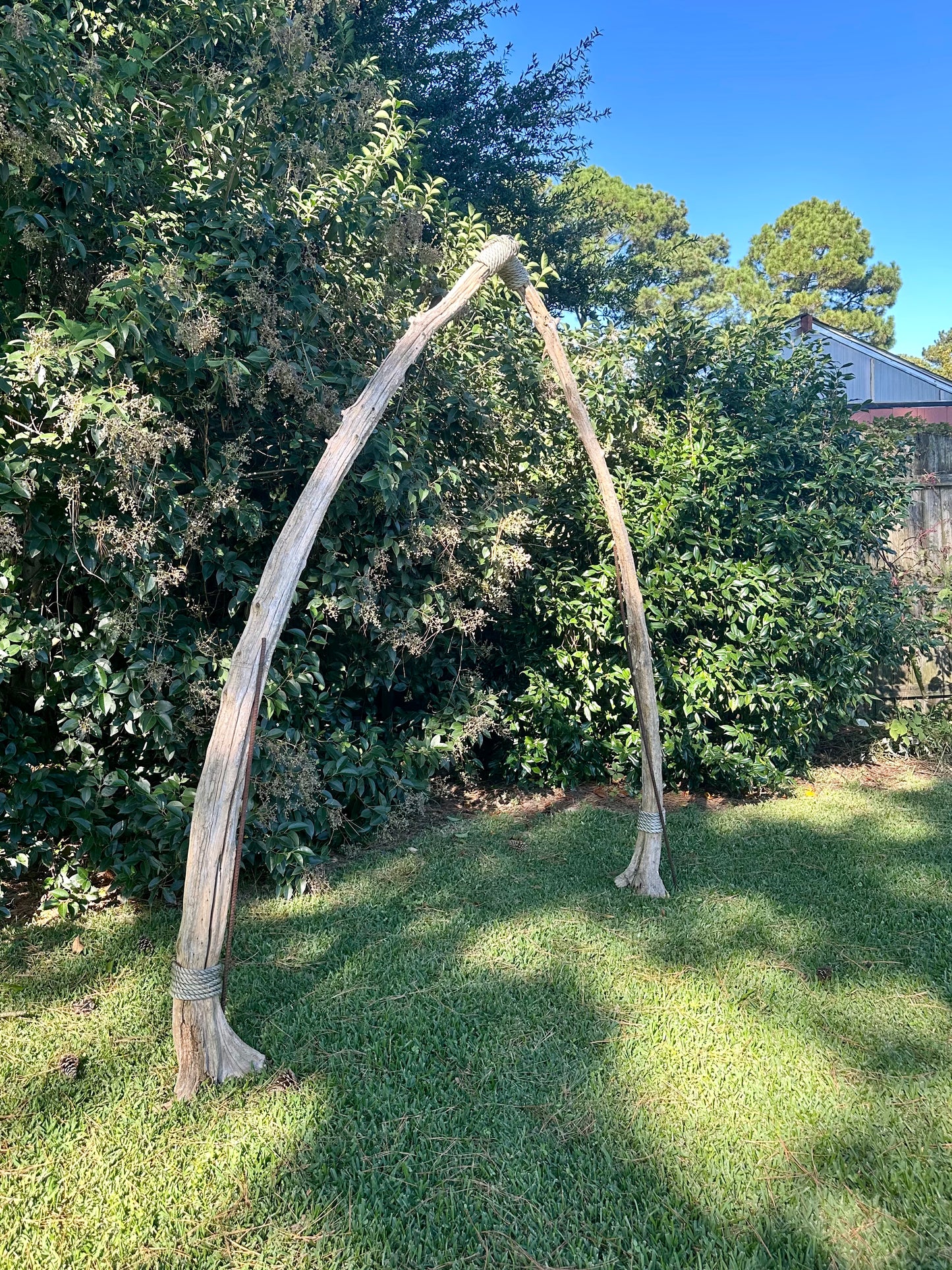 Large wooden archway in a grassy area with trees in the background