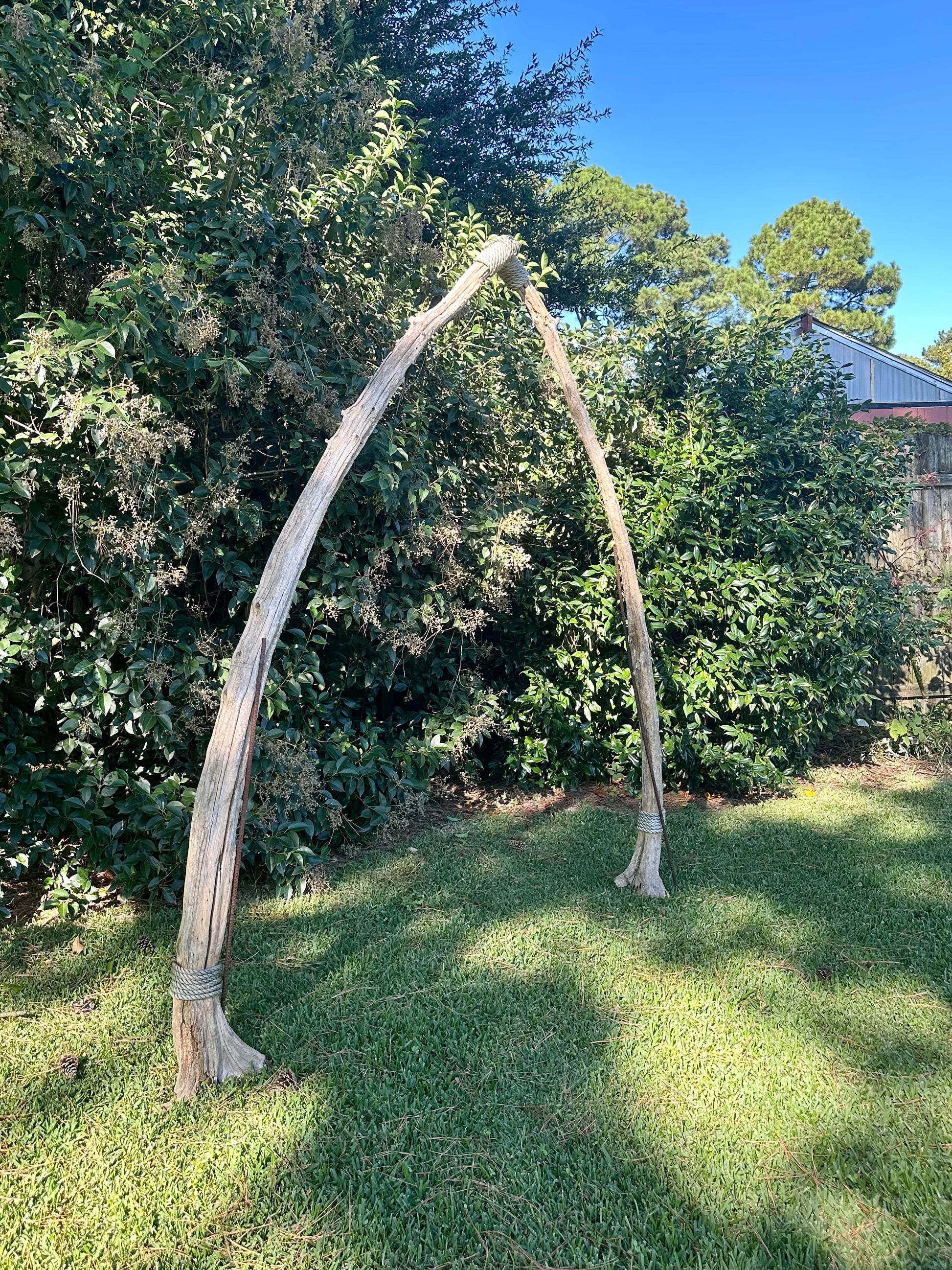 Large wooden archway in a grassy area with trees in the background