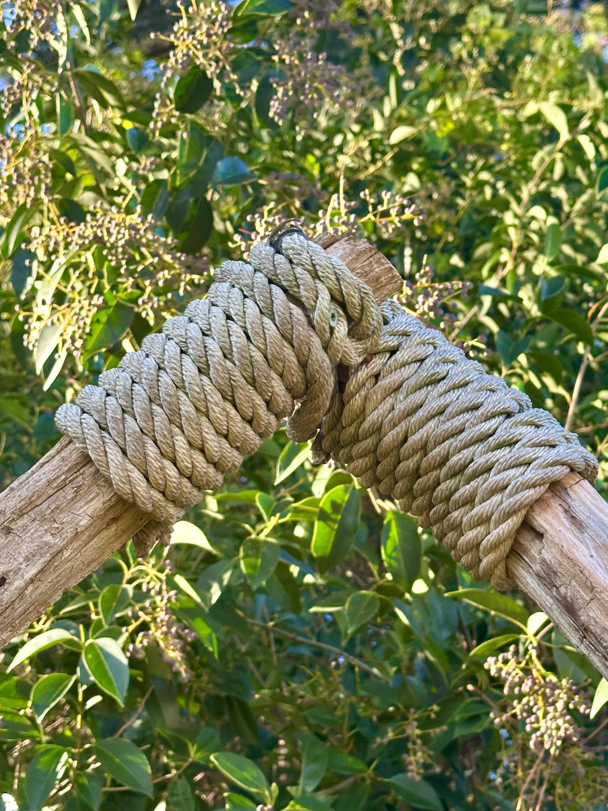 Closeup of wooden arch bound at the top by nautical rope.