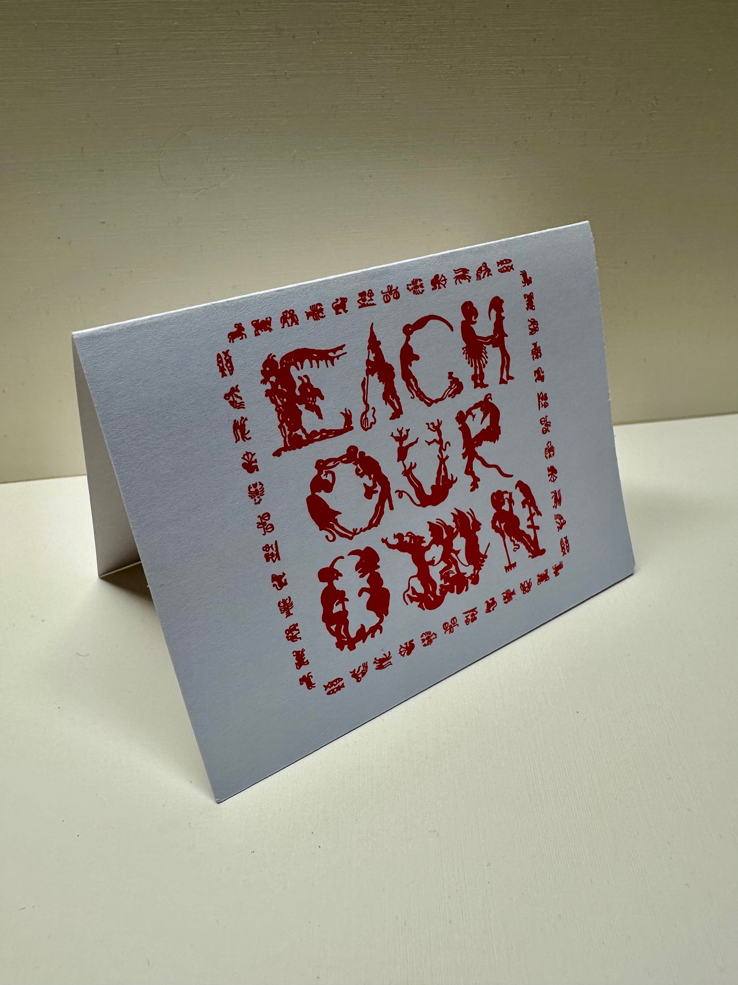 Front view of the 'Each Our Own' greeting card. Folded in half in landscape orientation.