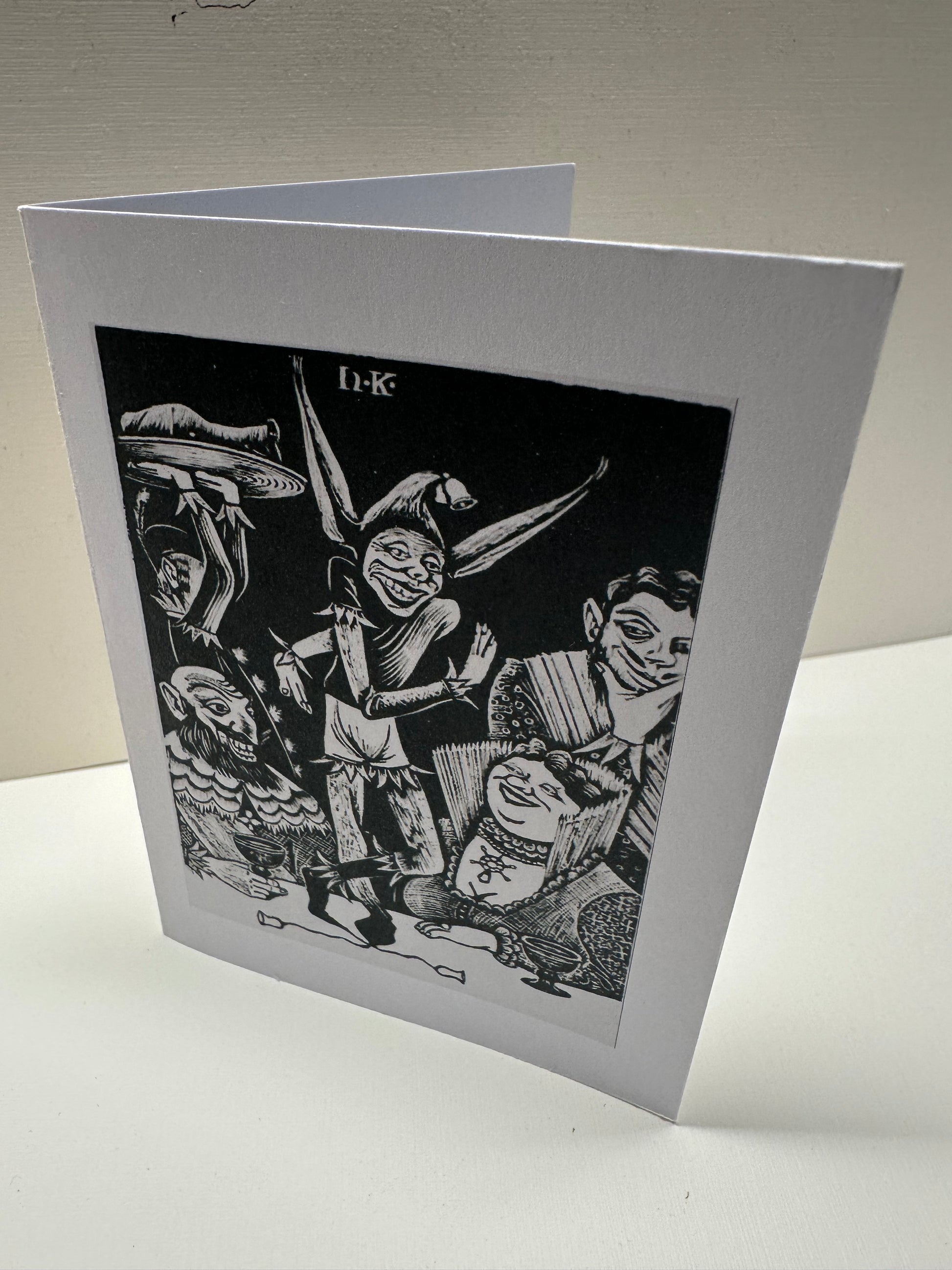 Front view of 'Fool at a Banquet' card. It is standing in portrait style, and opens to the right.