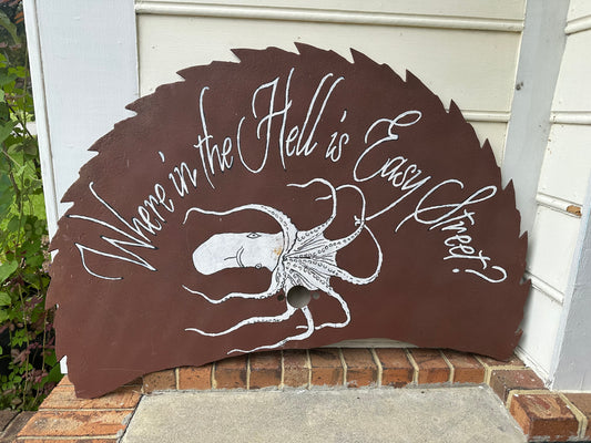 Decorative sign with an octopus design and text on a brown background, leaning against a white wall.