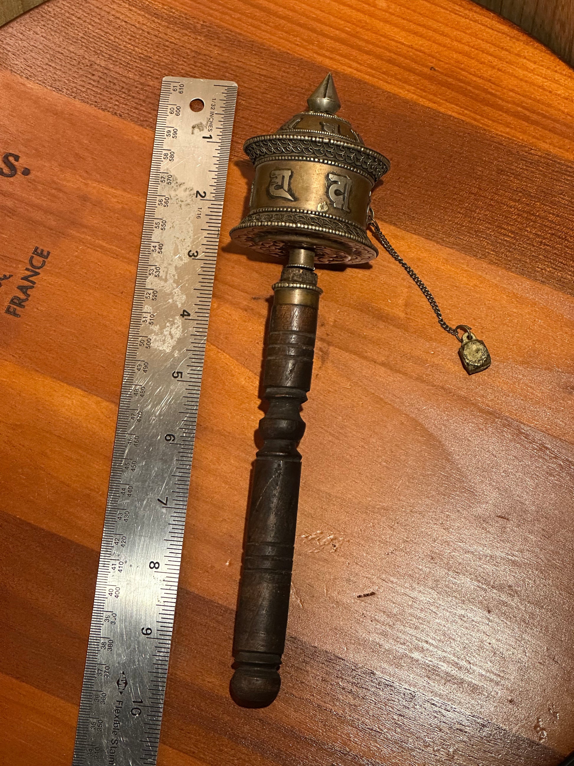 Small metal object on a wooden surface with a ruler for scale