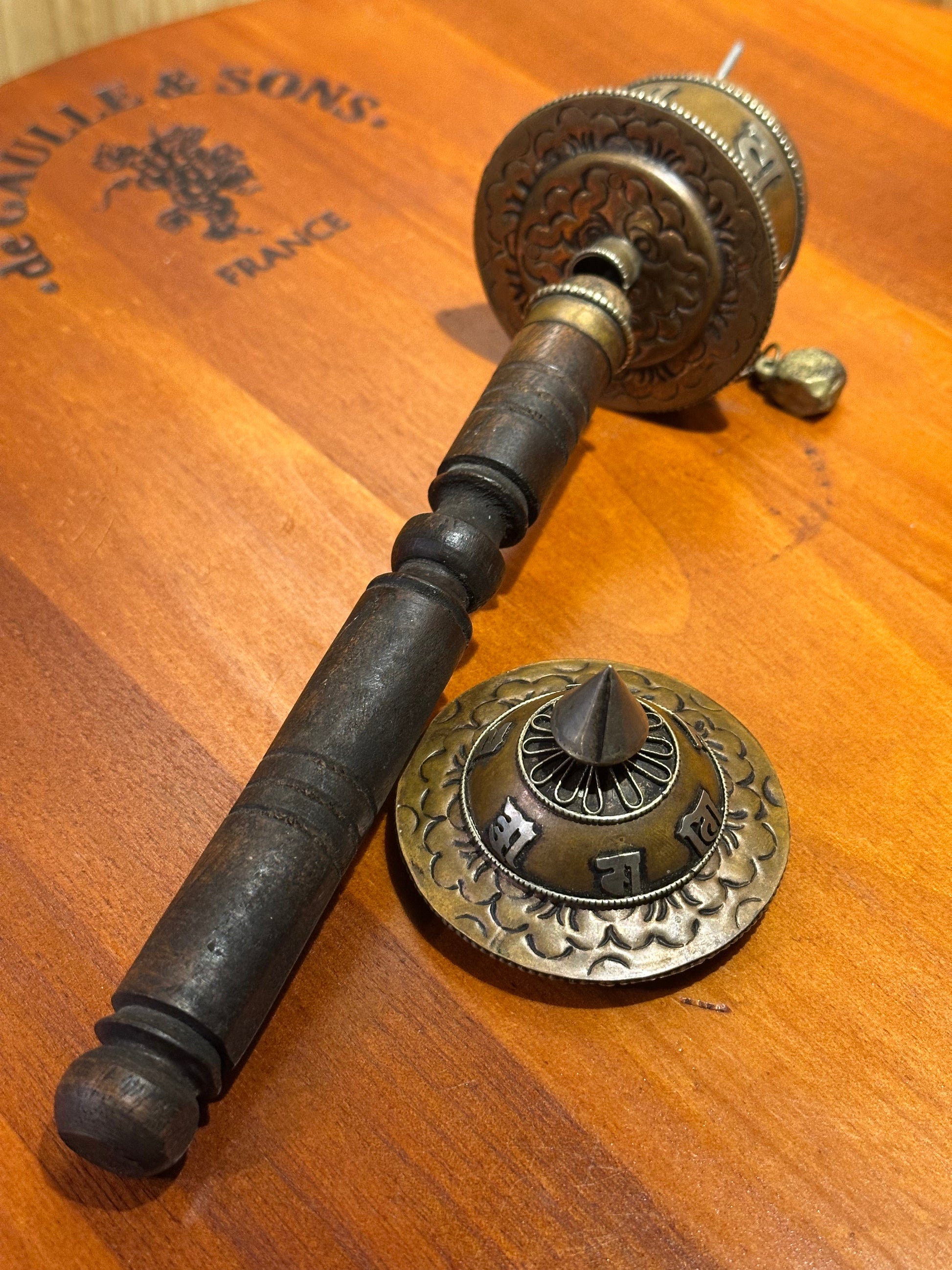 Decorative metal door handle on a wooden surface with visible branding.