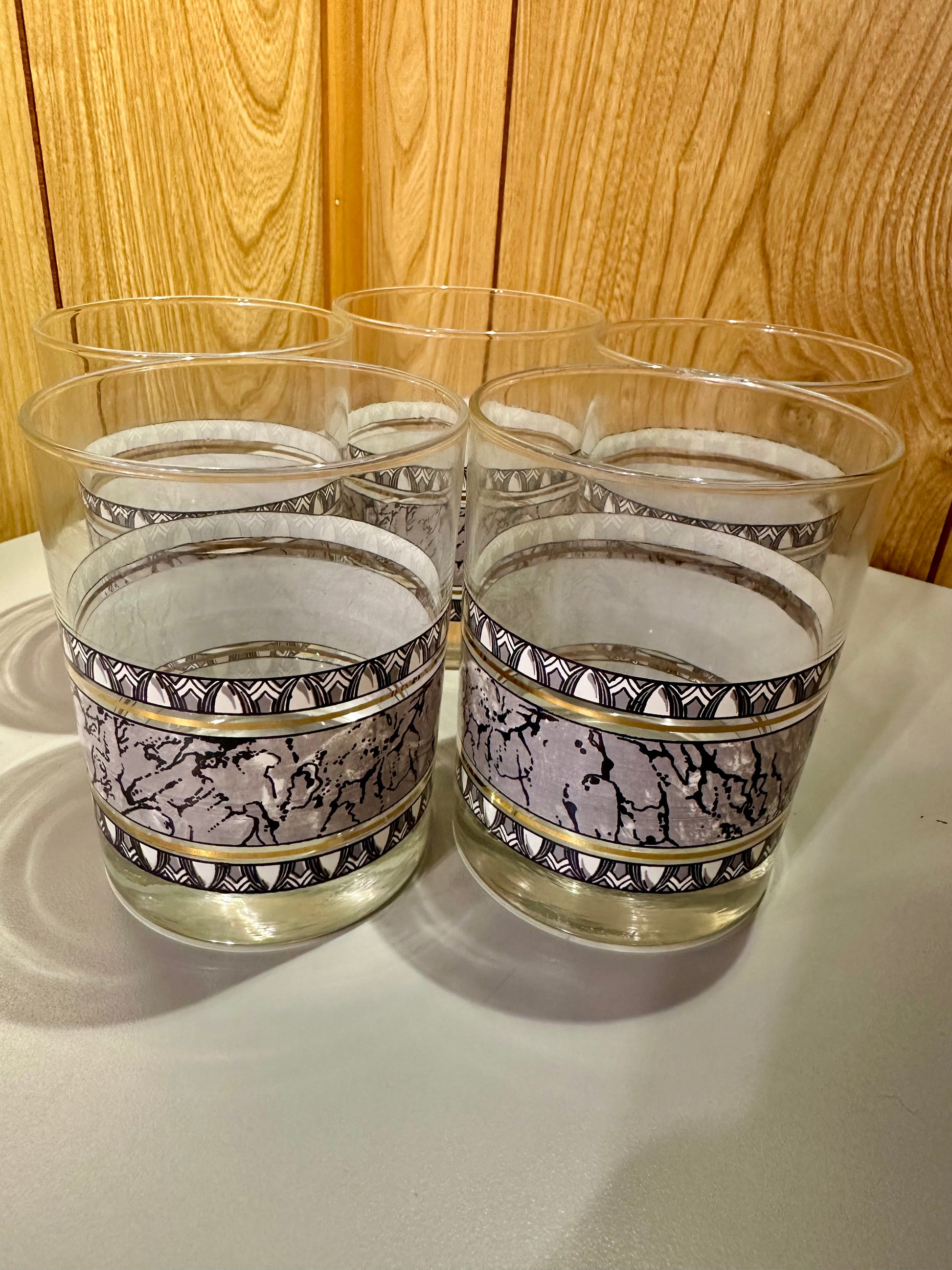 Set of five glasses with decorative bands on a gray surface