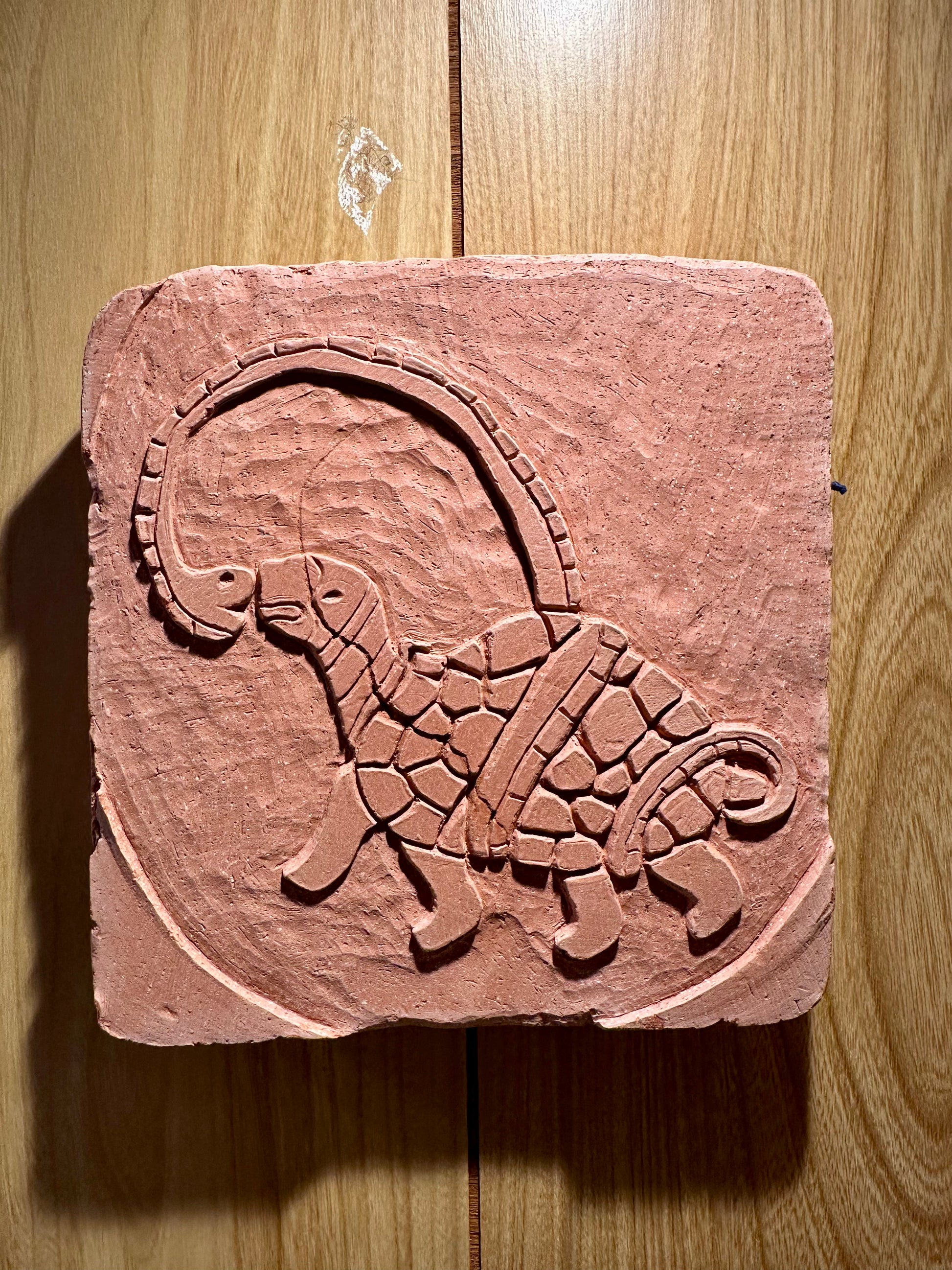 Decorative terracotta with turtle and snake design on a wooden surface