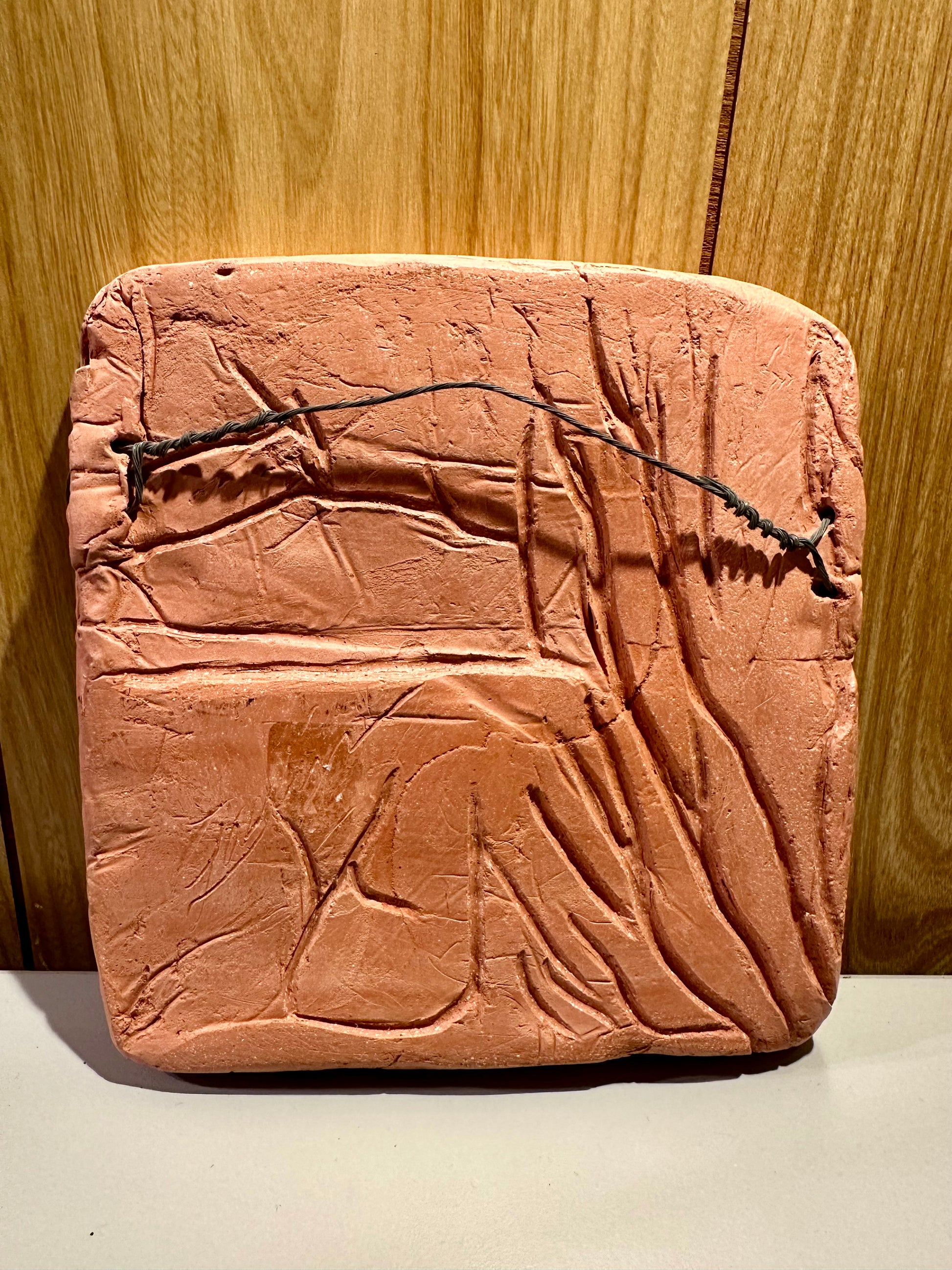 Back view of a clay tablet on a wooden surface