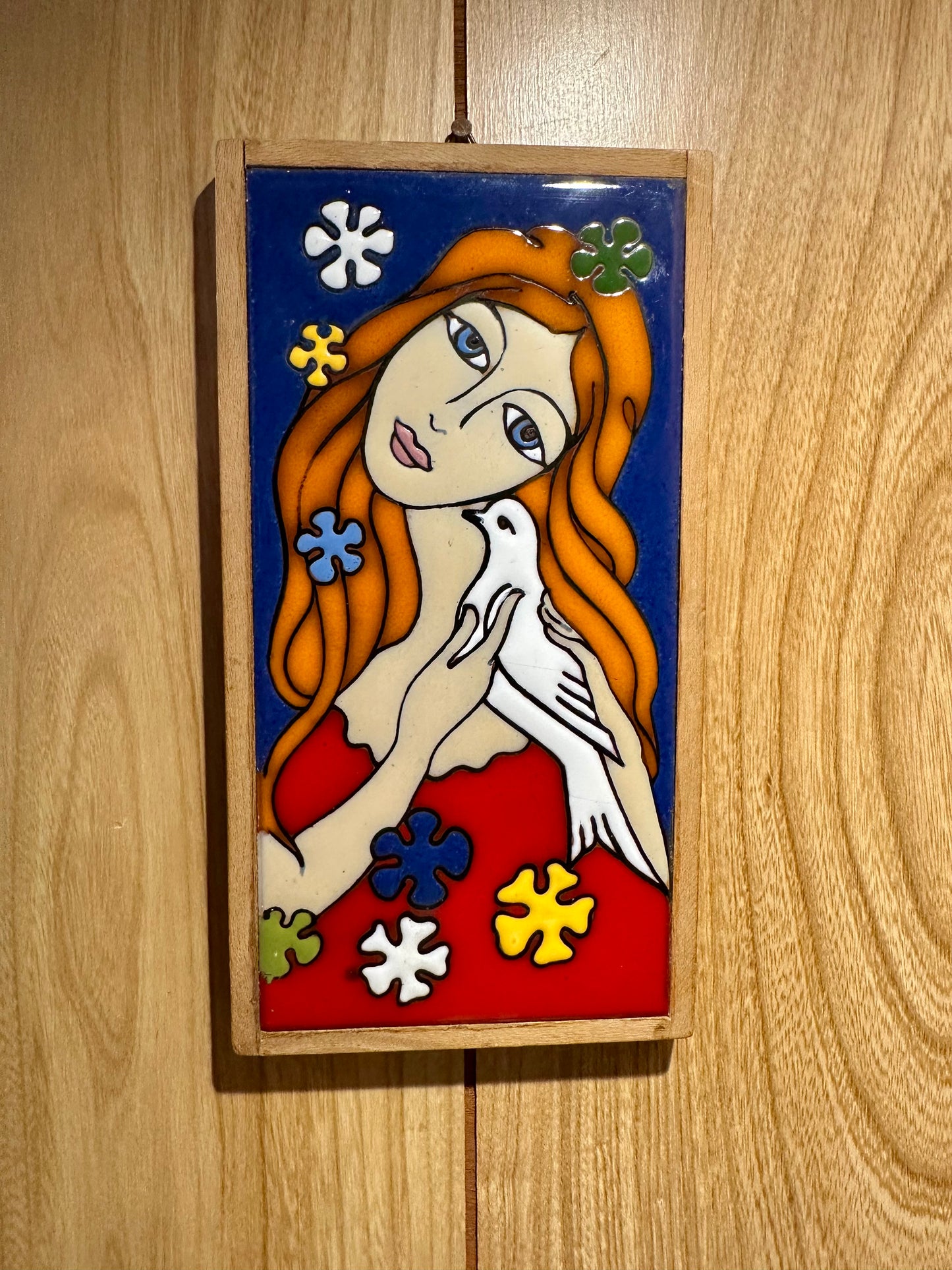 Decorative tile with a stylized illustration of a woman holding a dove on a wooden surface.