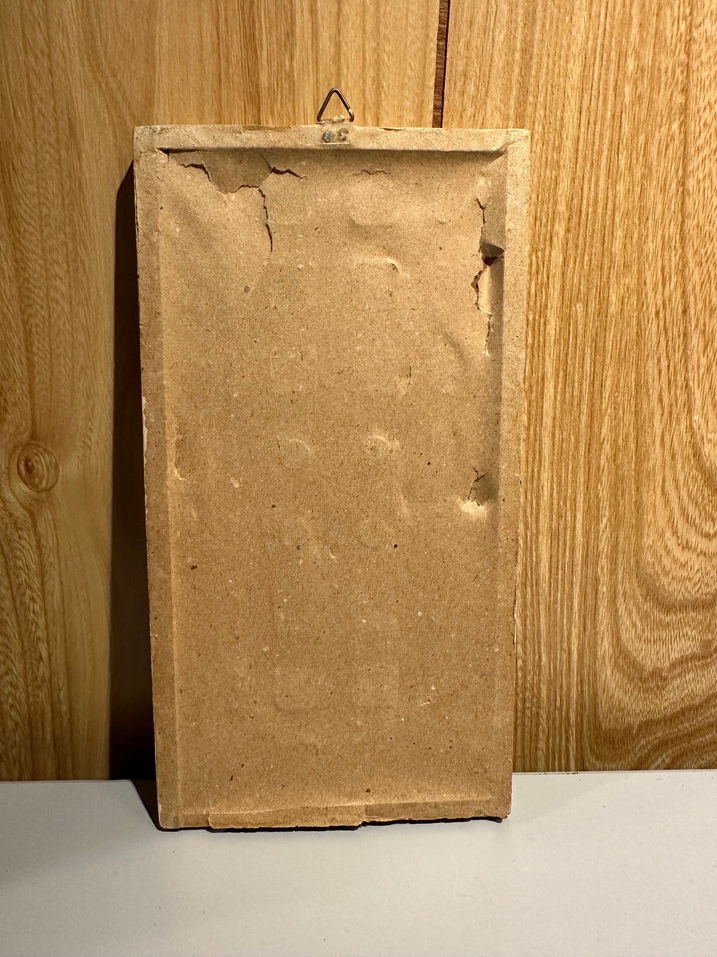 Rectangular back view of a dust cover on framed art against a wooden surface