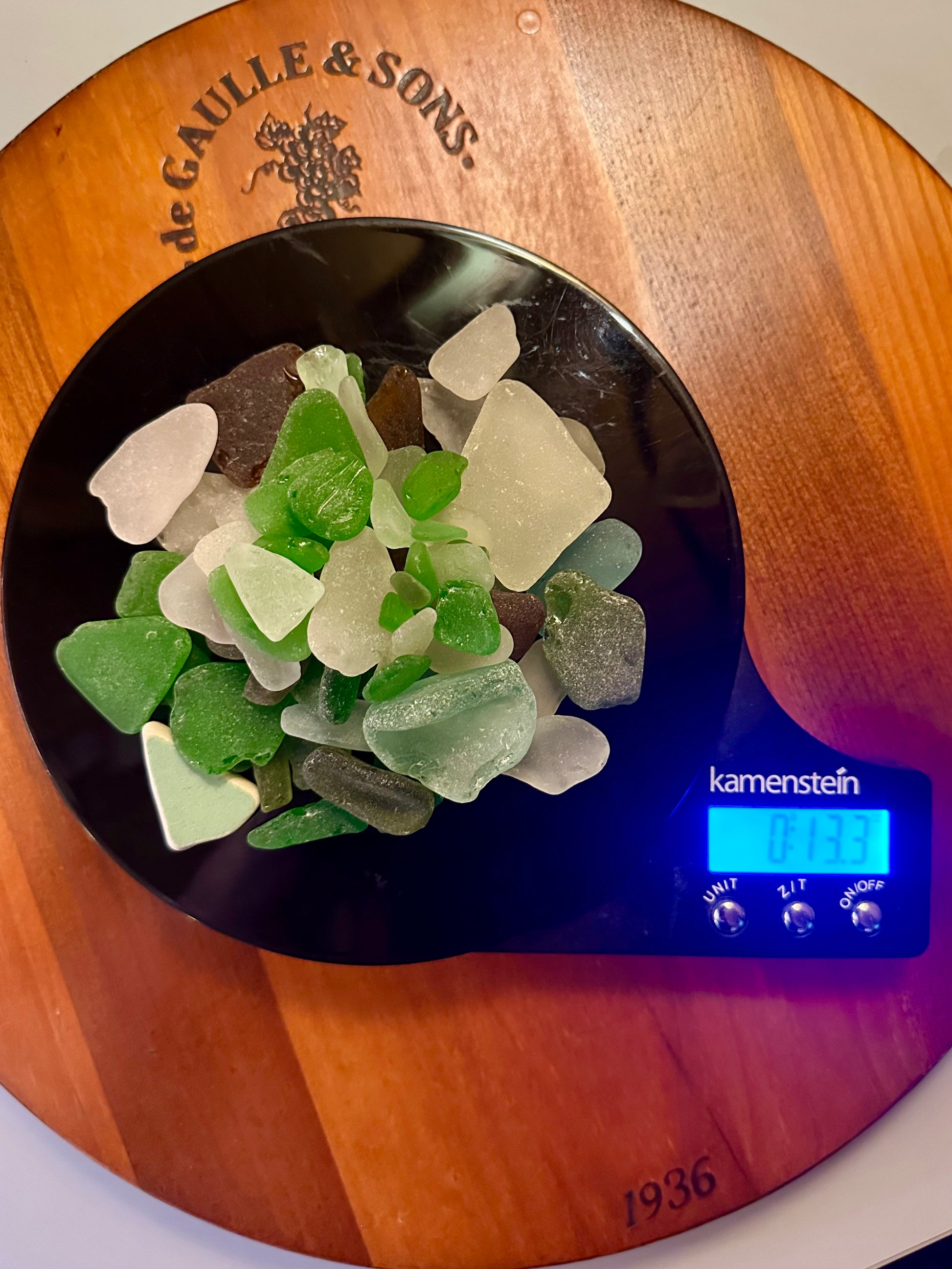 Sea glass pieces on a digital kitchen scale with 'kamenstein' branding.
