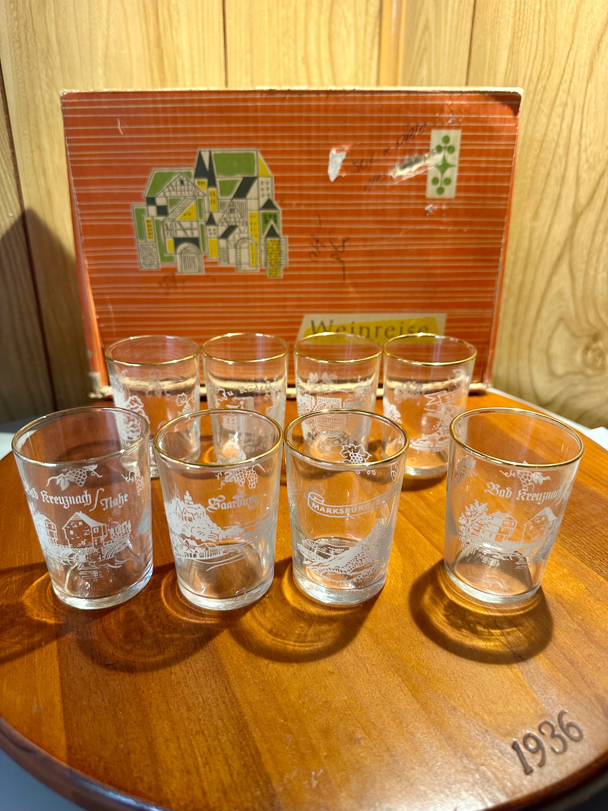Set of etched glass tumblers on a wooden surface with a vintage box in the background.