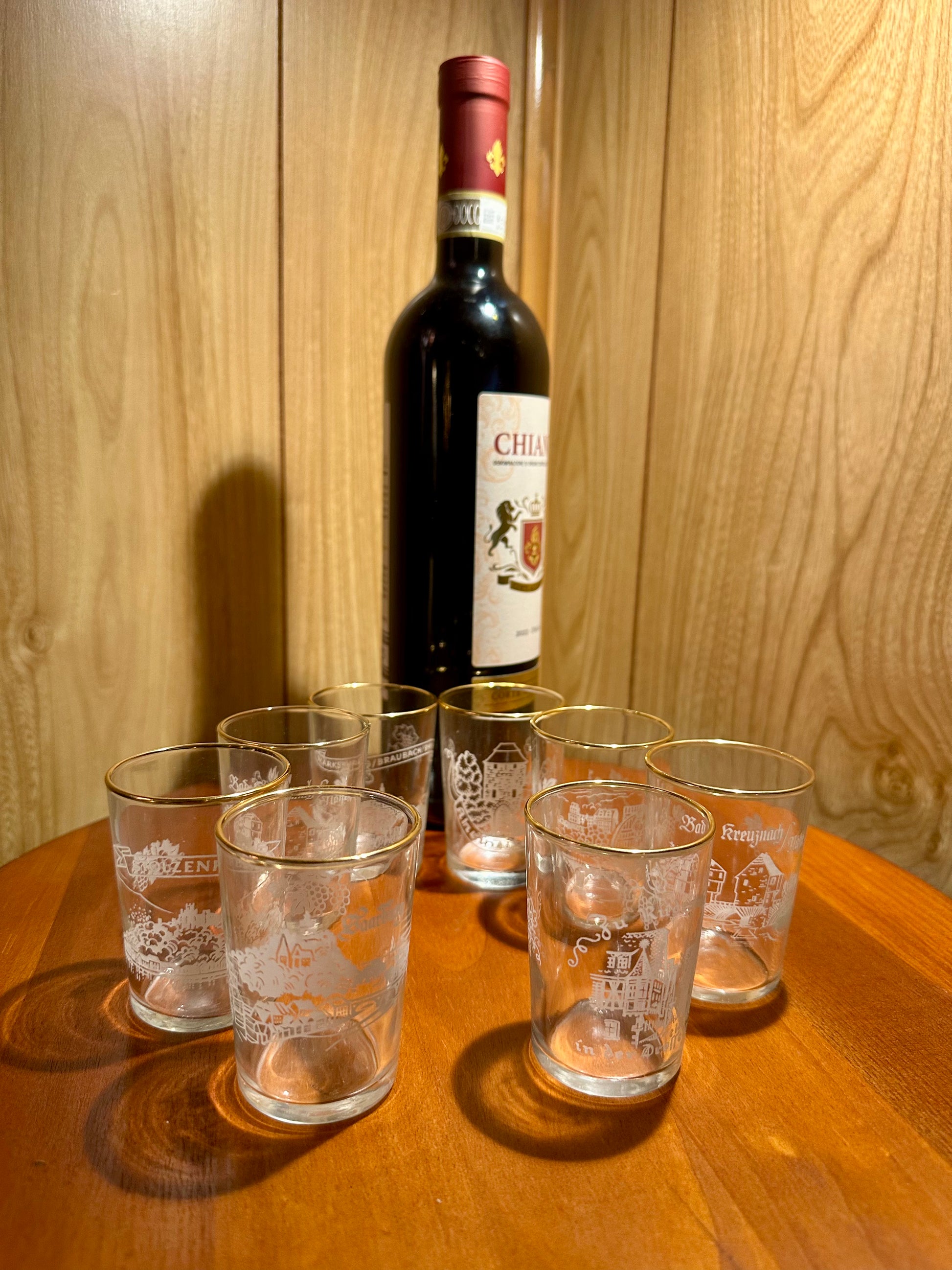 Bottle of Chianti wine with six shot glasses on a wooden surface