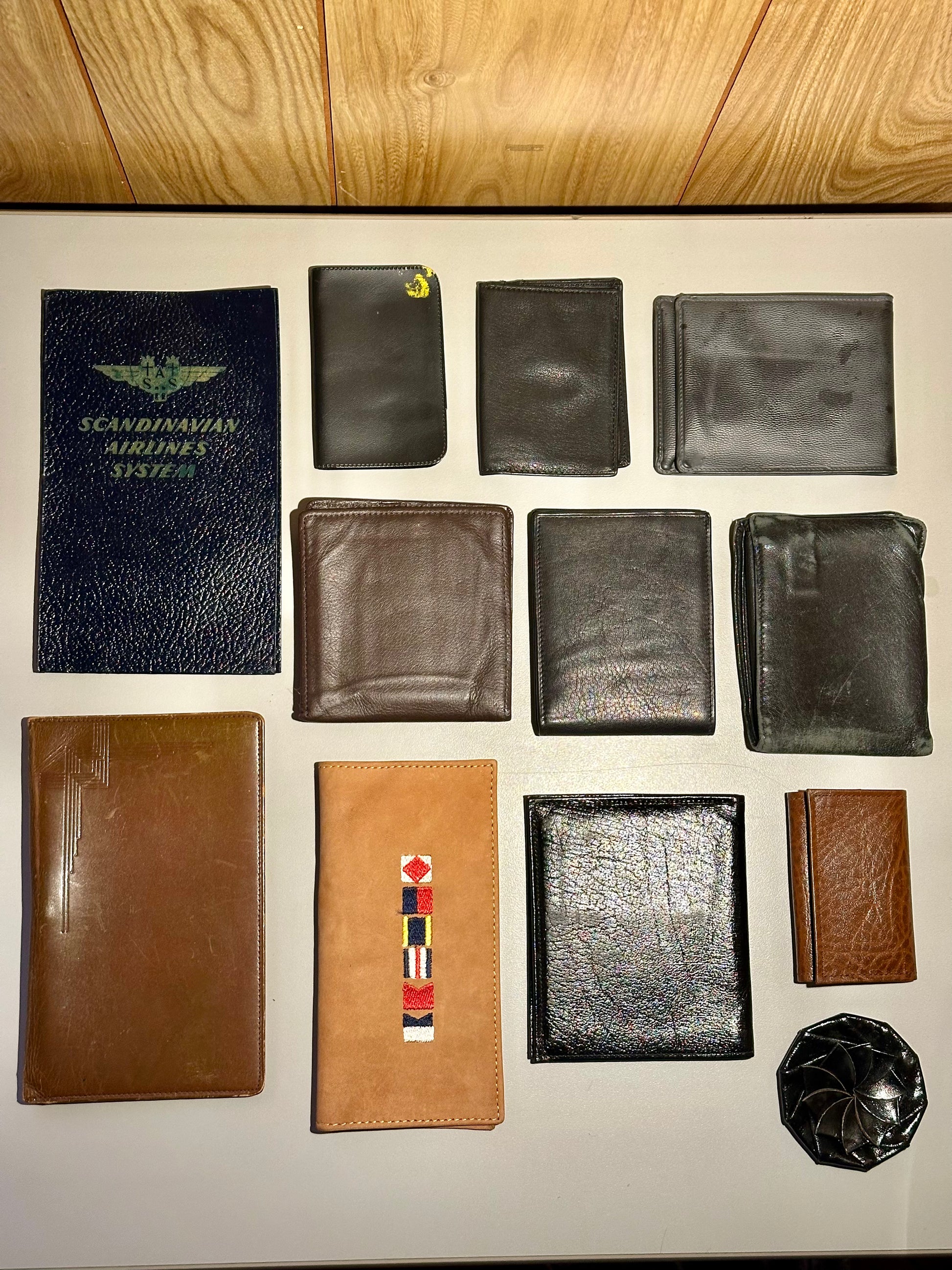 Collection of various leather wallets on a light-colored surface with a wooden background.
