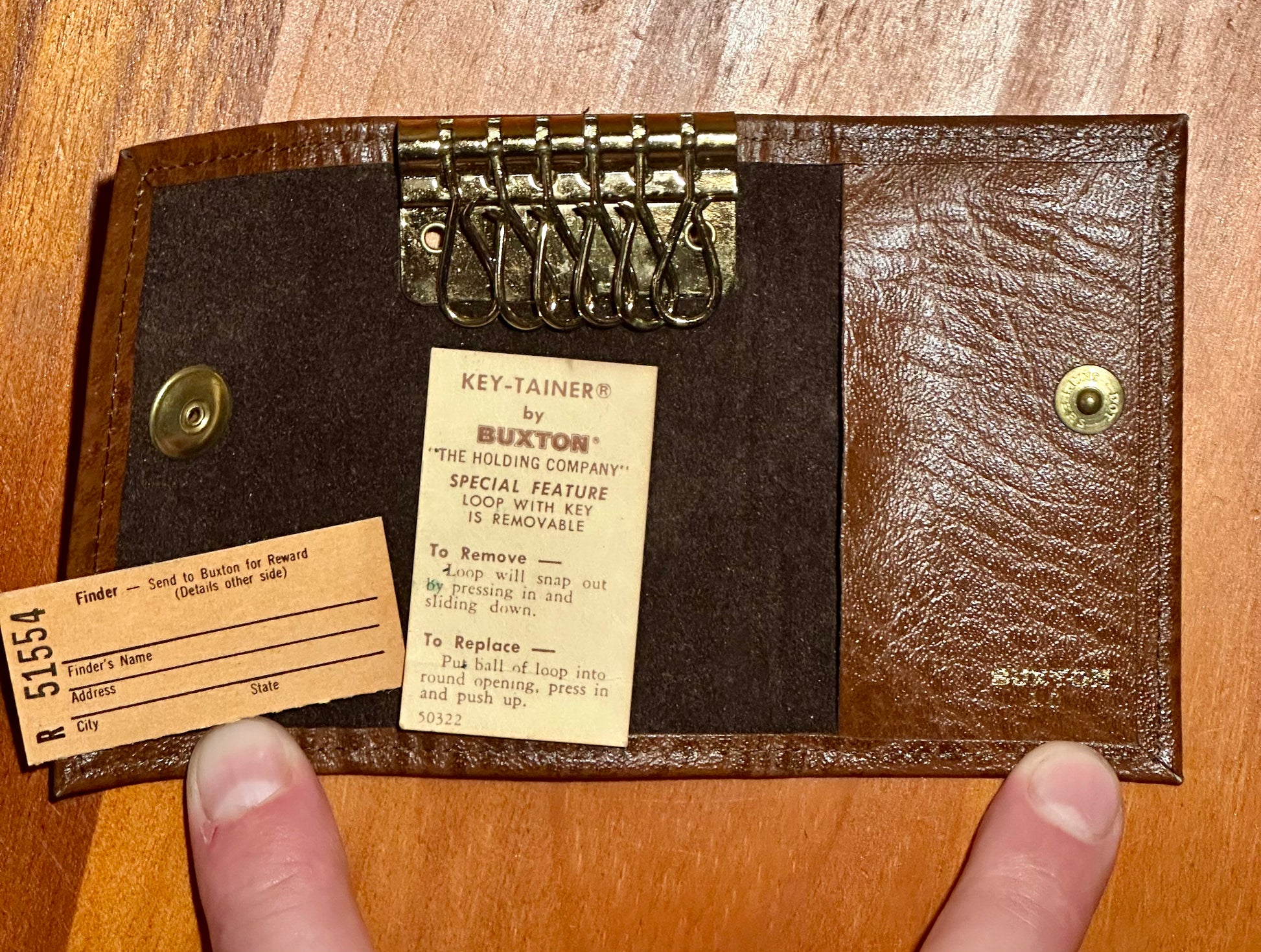 Brown leather key holder with keys and labels on a wooden surface
