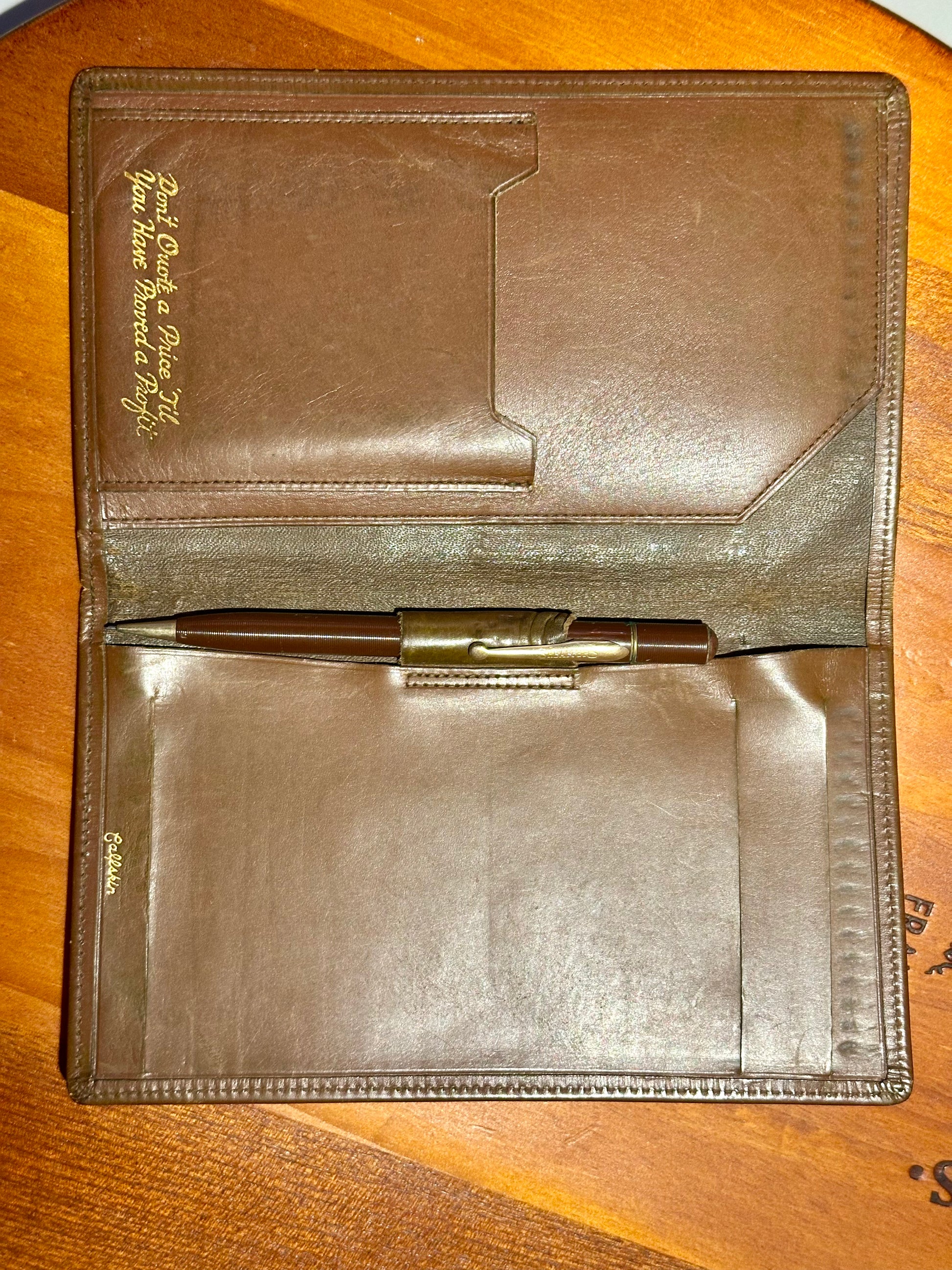 Brown leather portfolio with pen on a wooden surface
