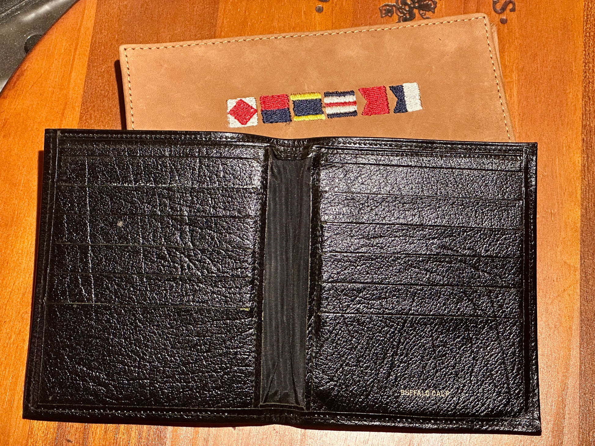 Black leather wallet with a decorative flap on a wooden surface