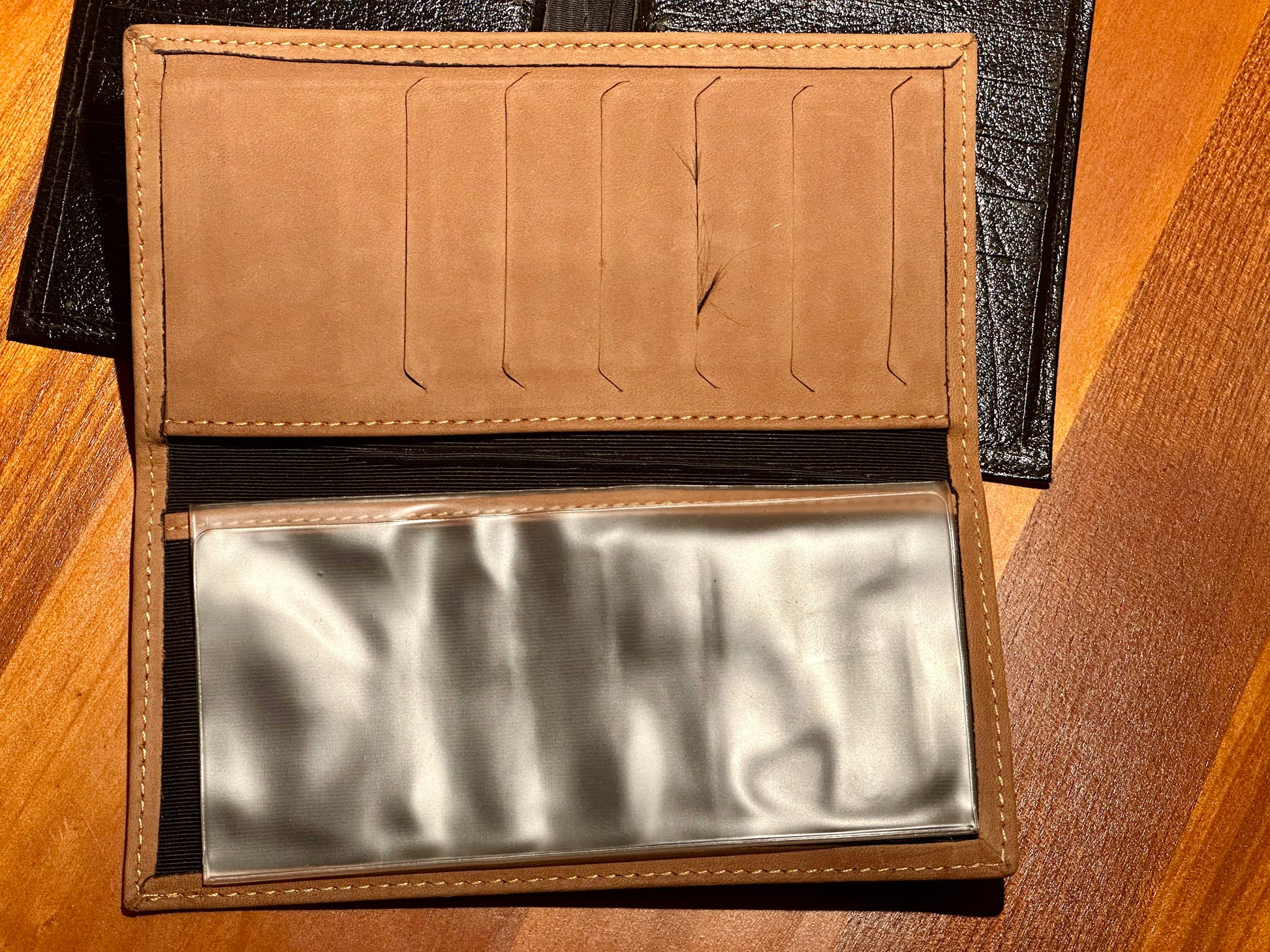 Brown leather wallet with a metallic interior on a wooden surface