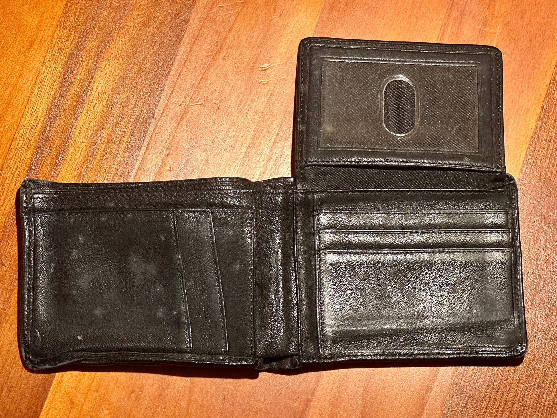 Black leather wallet on a wooden surface
