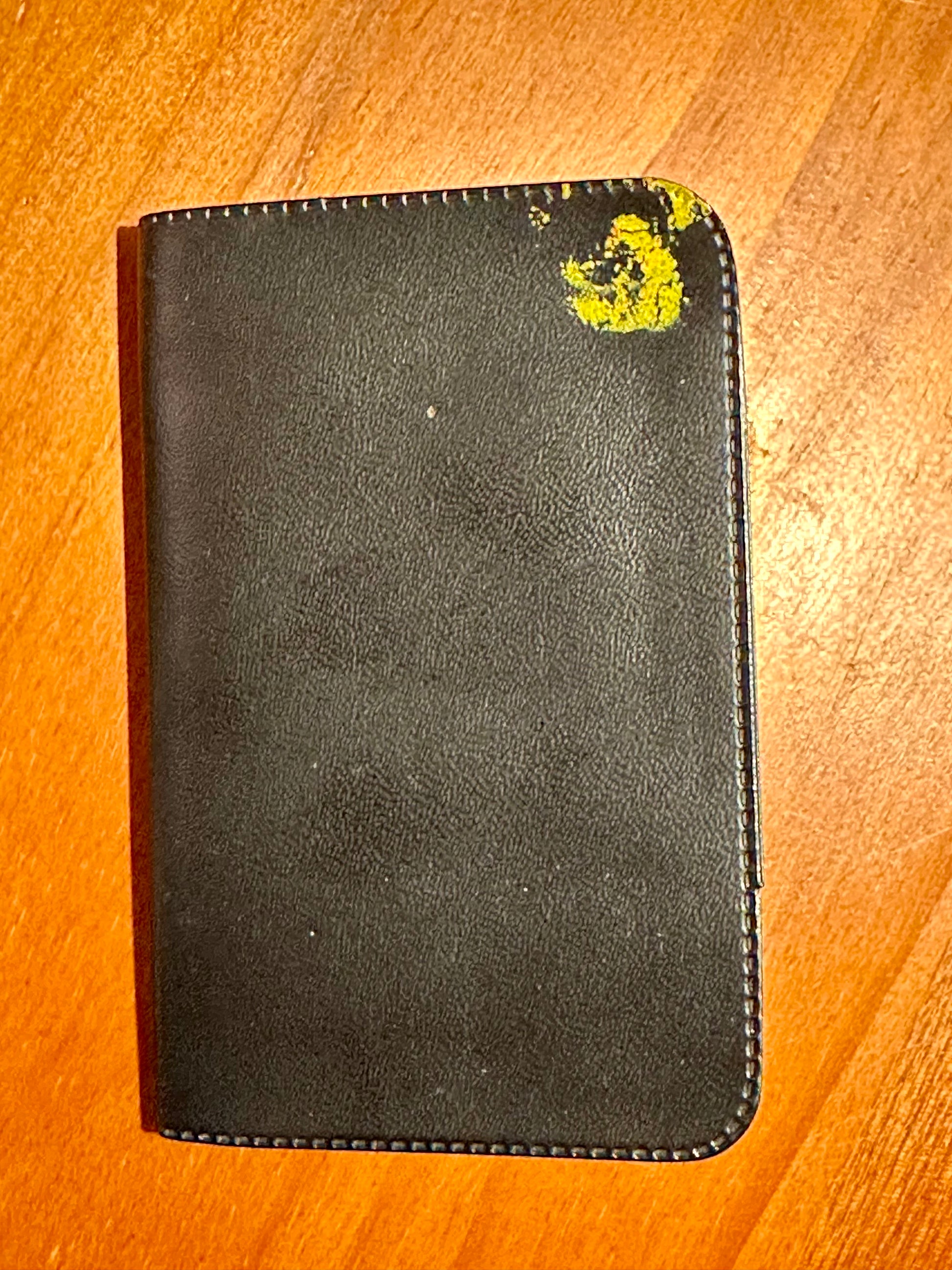 Black leather wallet with a yellow logo on a wooden surface