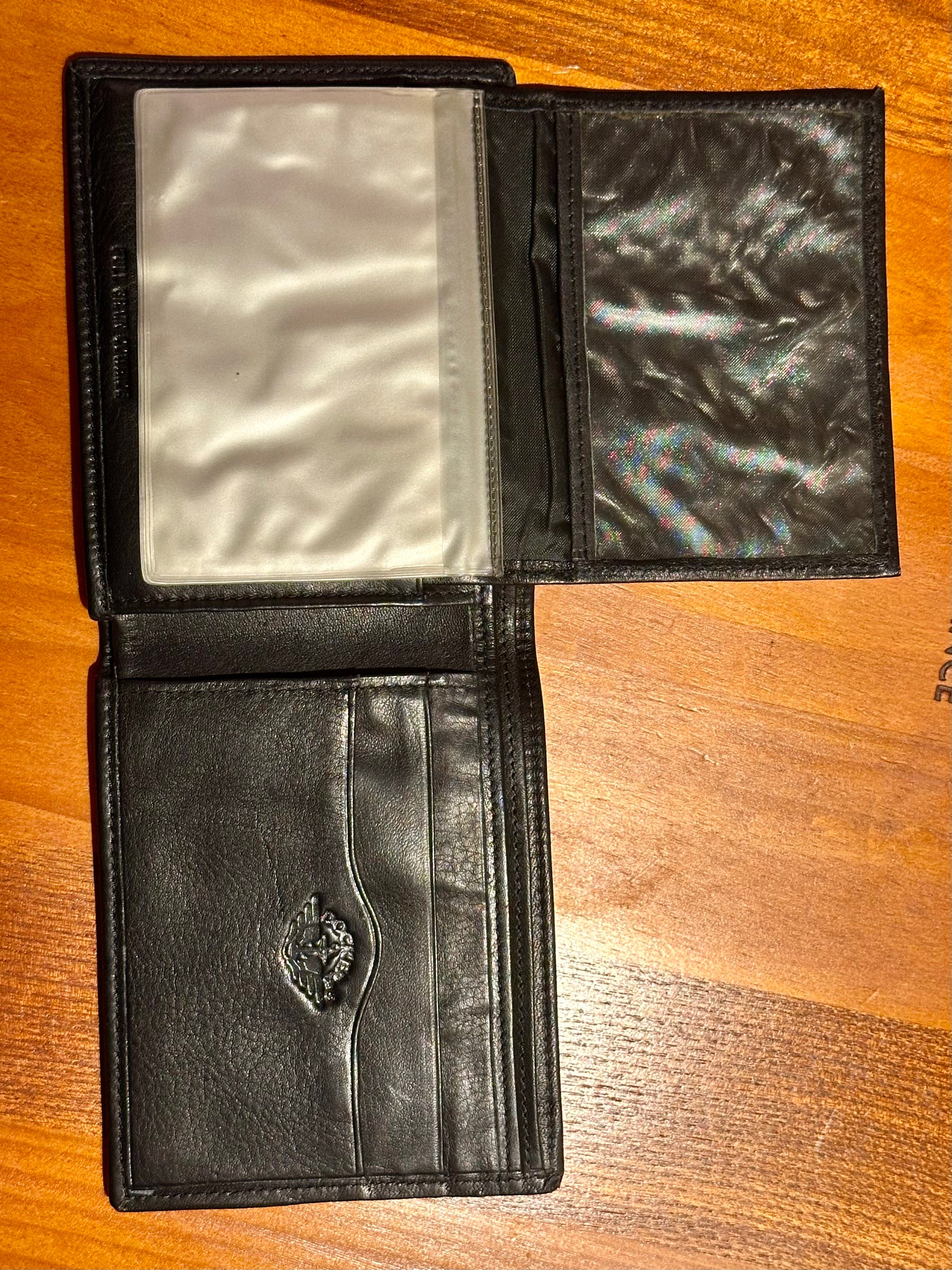 Black leather wallet open on a wooden surface