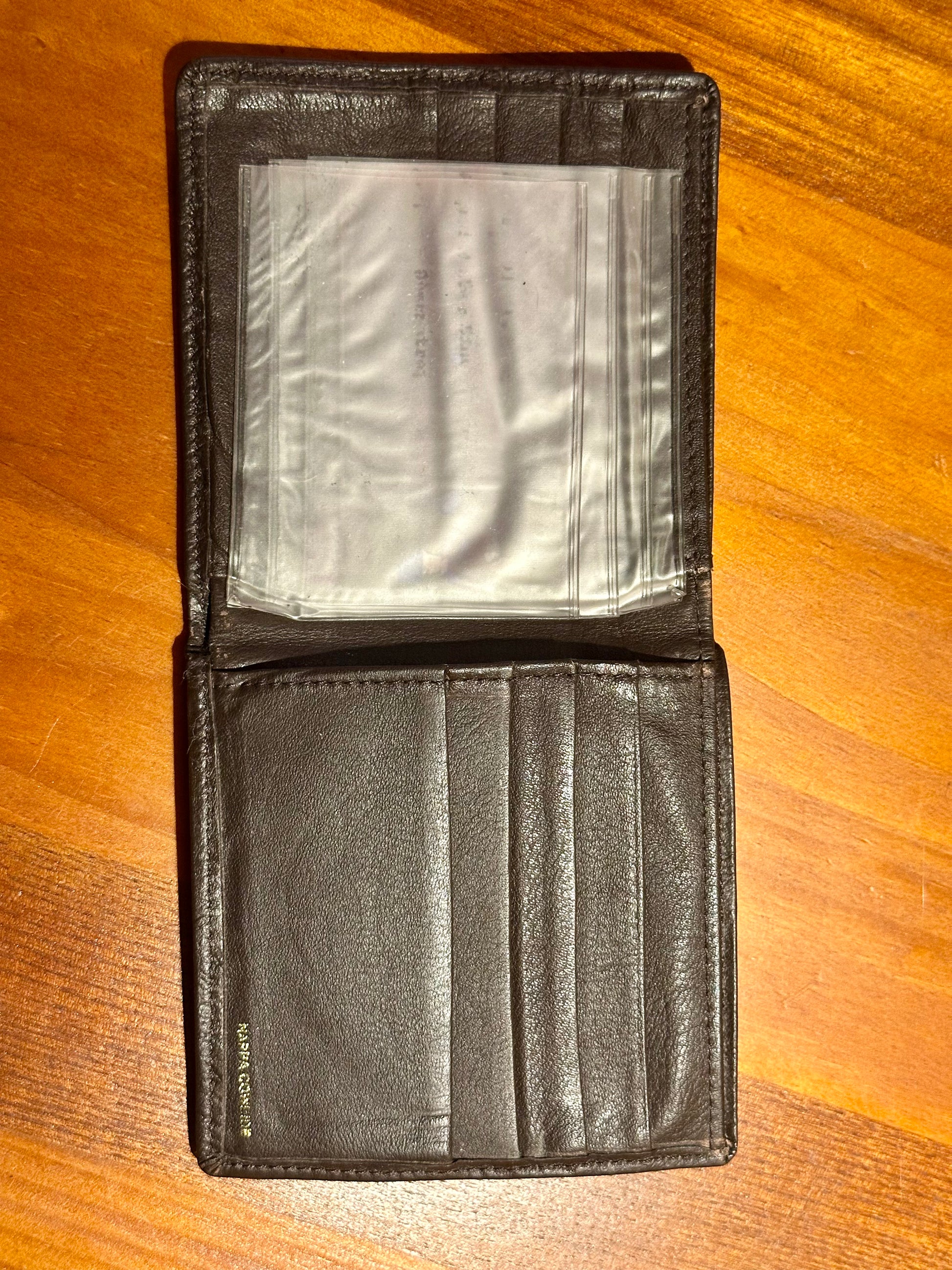 Black leather wallet open on a wooden surface