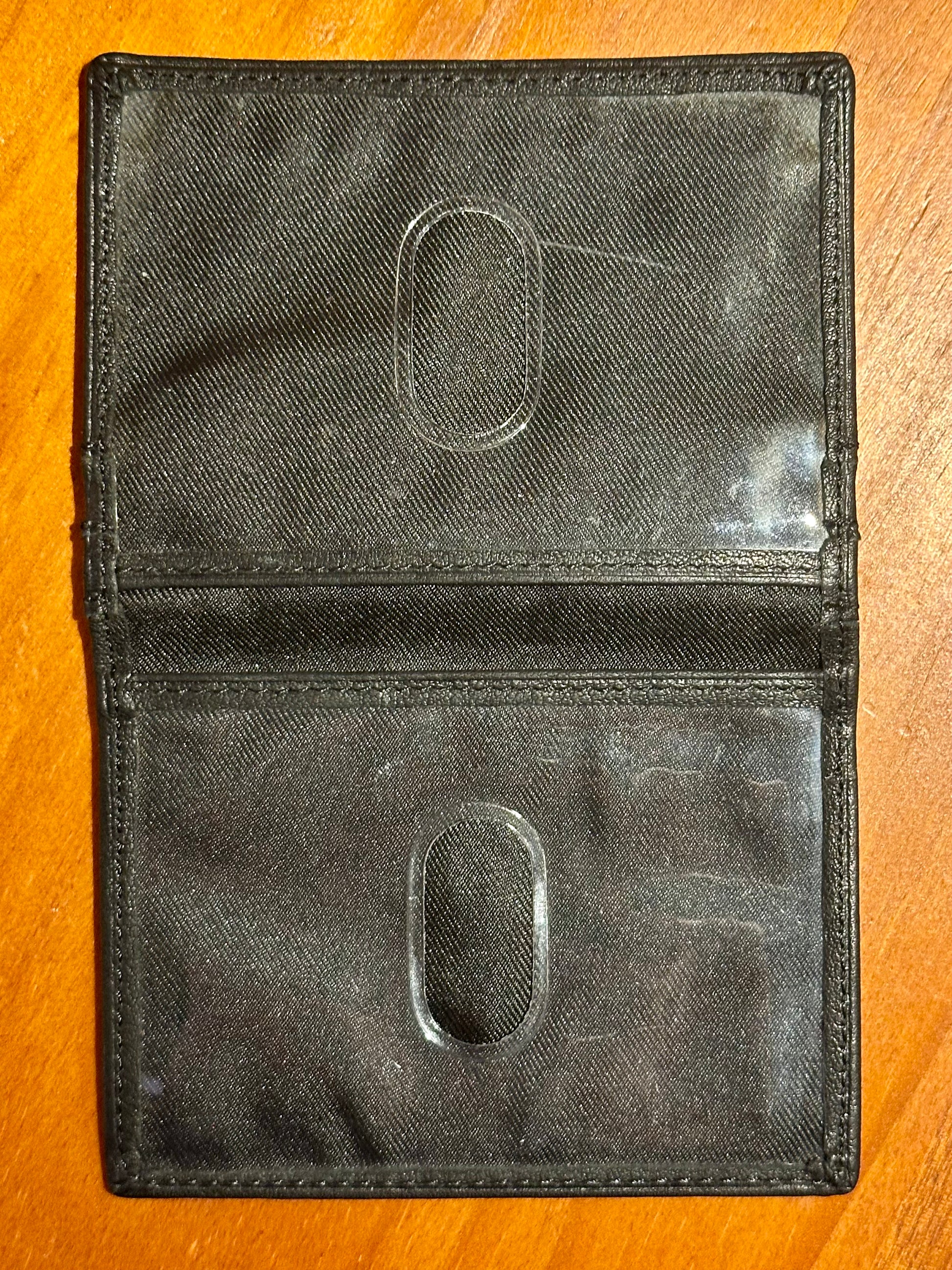Black leather wallet with brand logo on a wooden surface