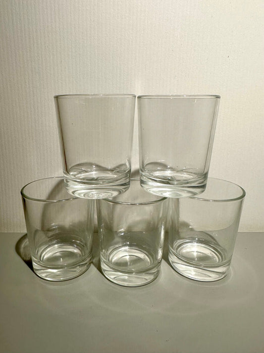 Five clear glass tumblers on a light surface with a neutral background