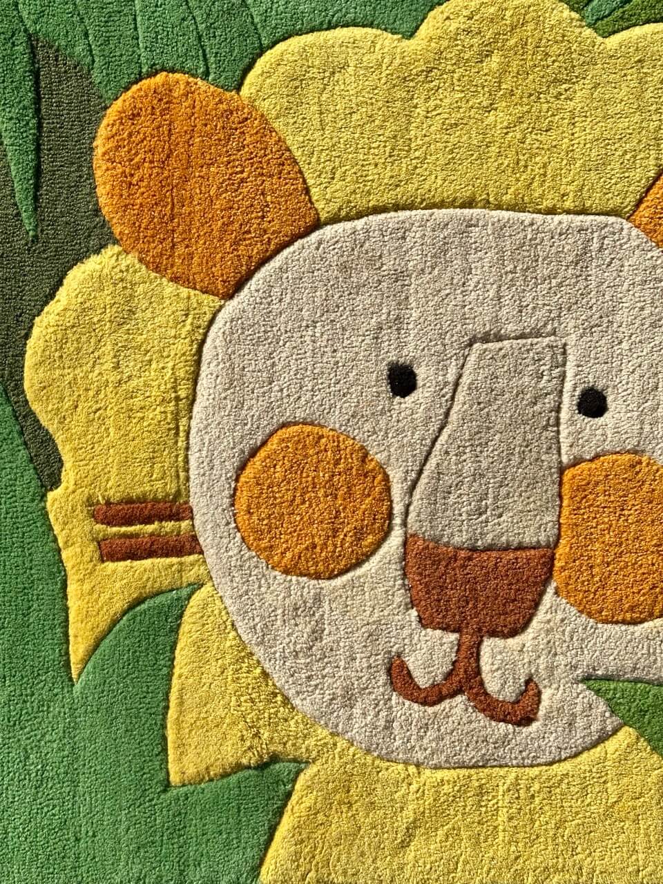 Close-up of a lion-shaped rug with yellow, orange, and green colors.