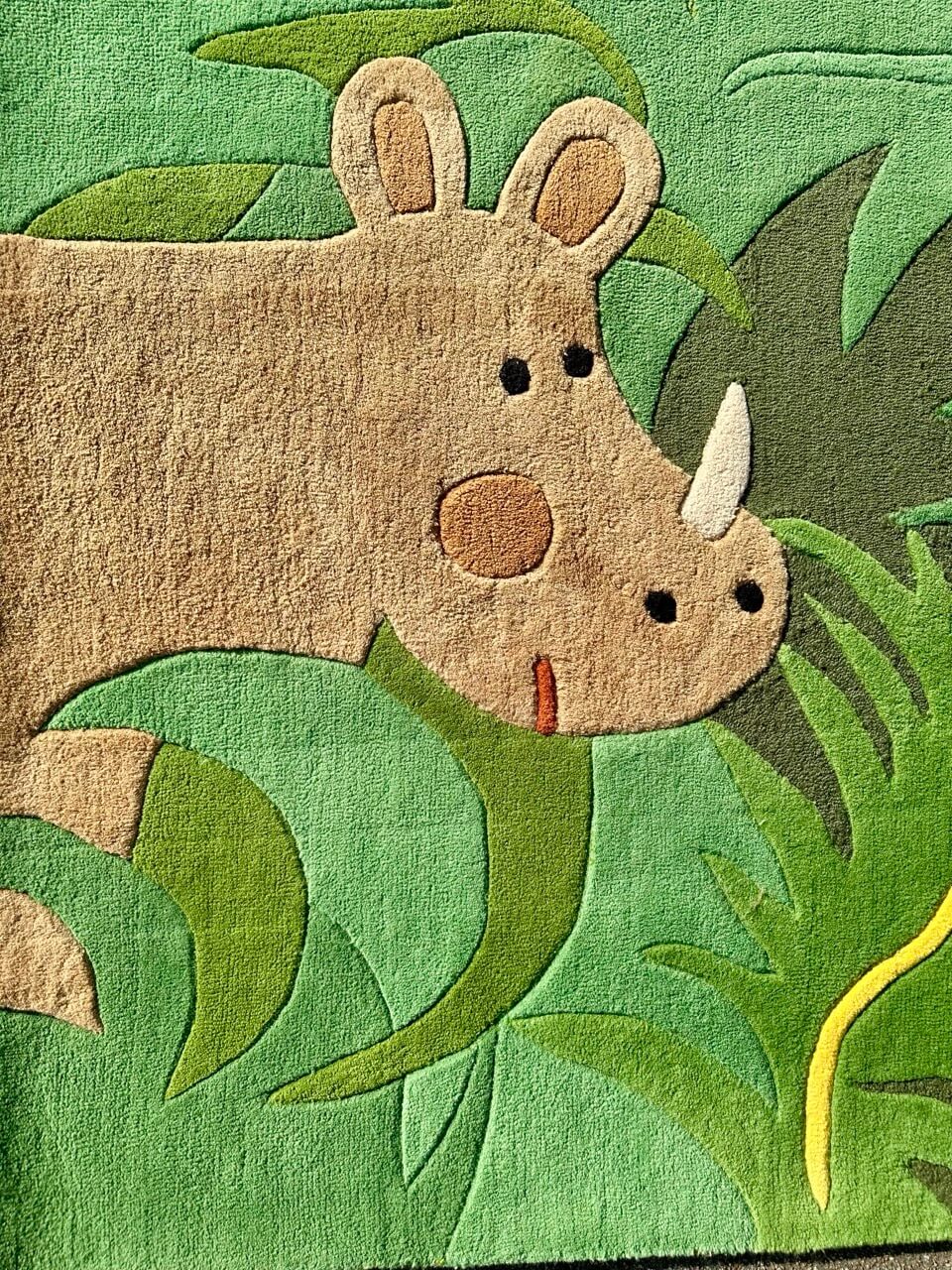 Children's rug with a rhinoceros design on a green background