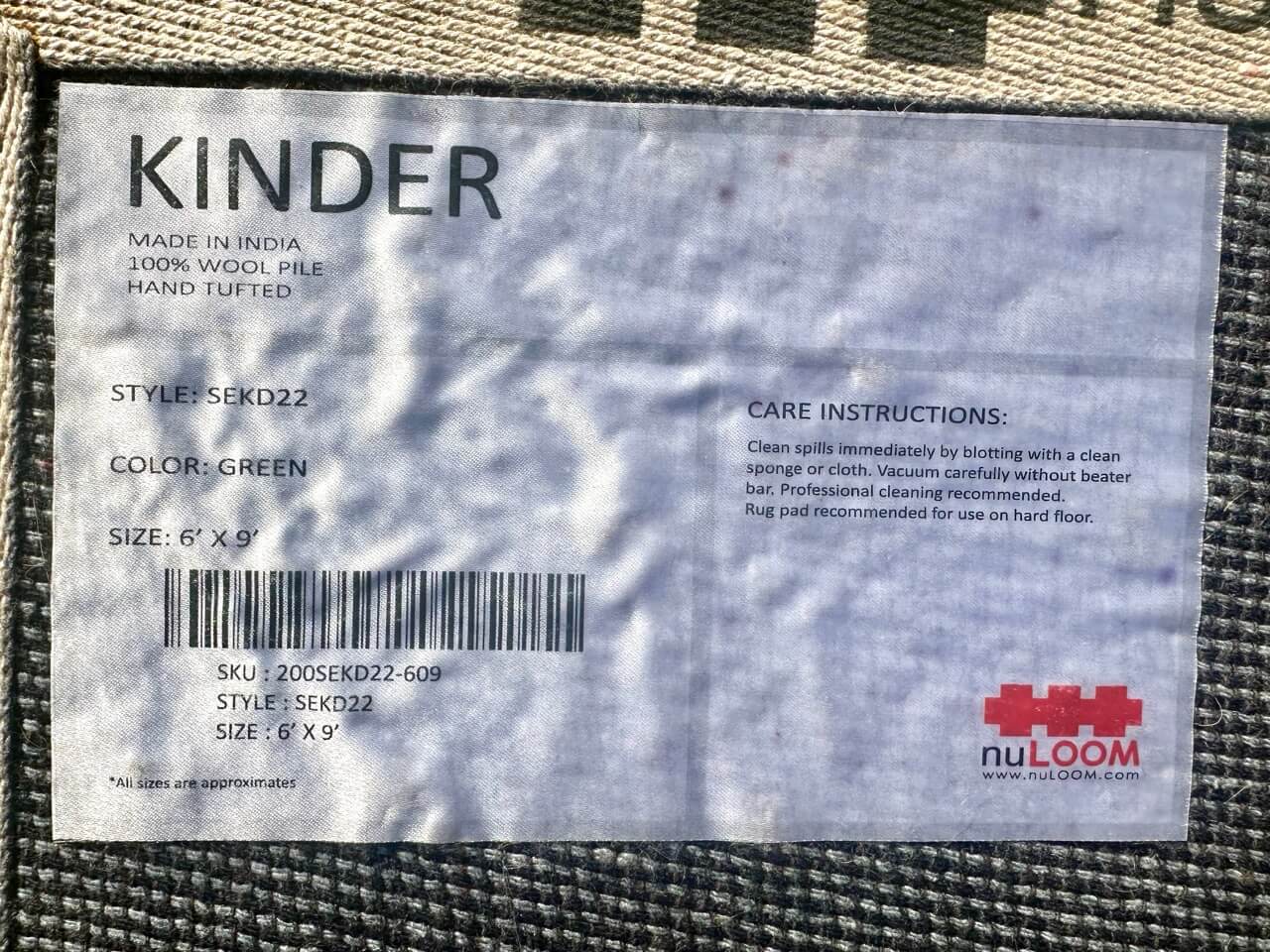 Label on a rug with 'Kinder' and 'nuLOOM' branding and care instructions.