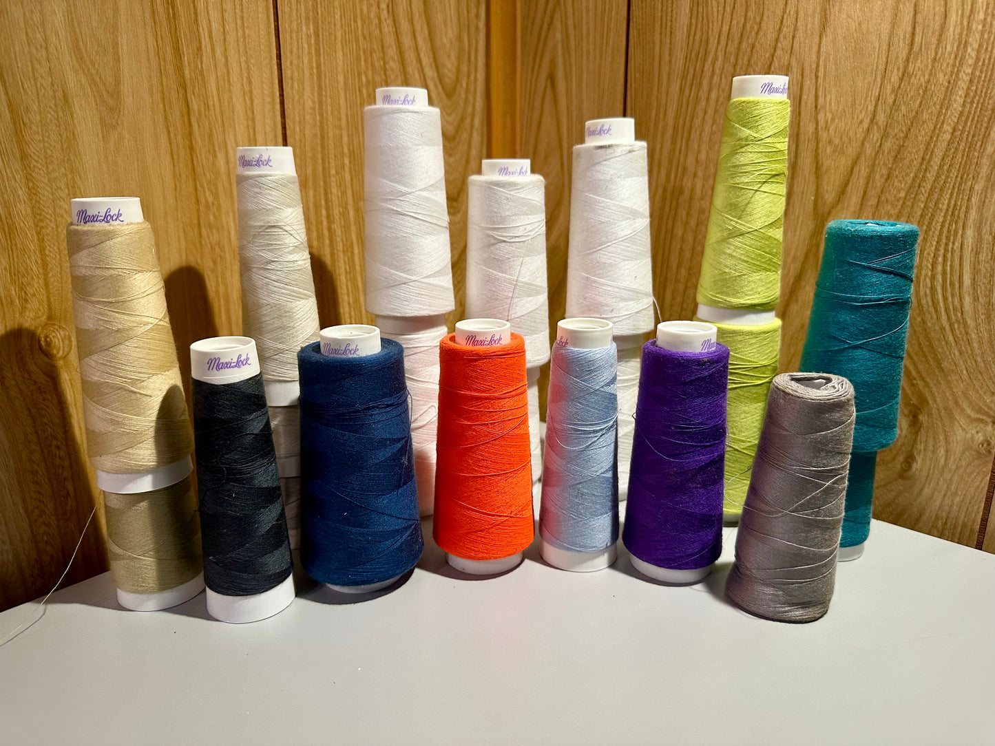 Assorted spools of thread in various colors on a wooden surface