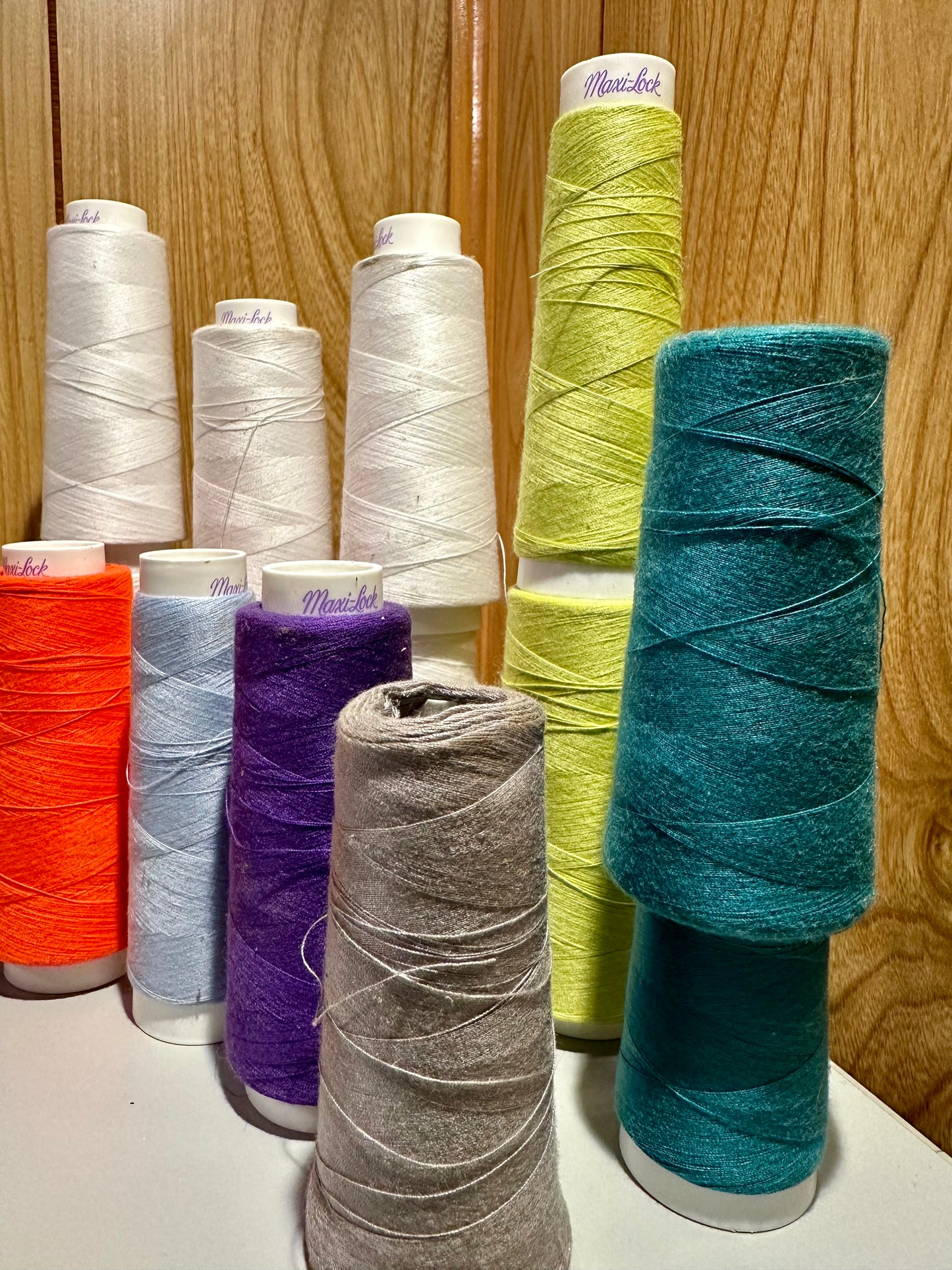 Assorted spools of thread in various colors on a wooden surface