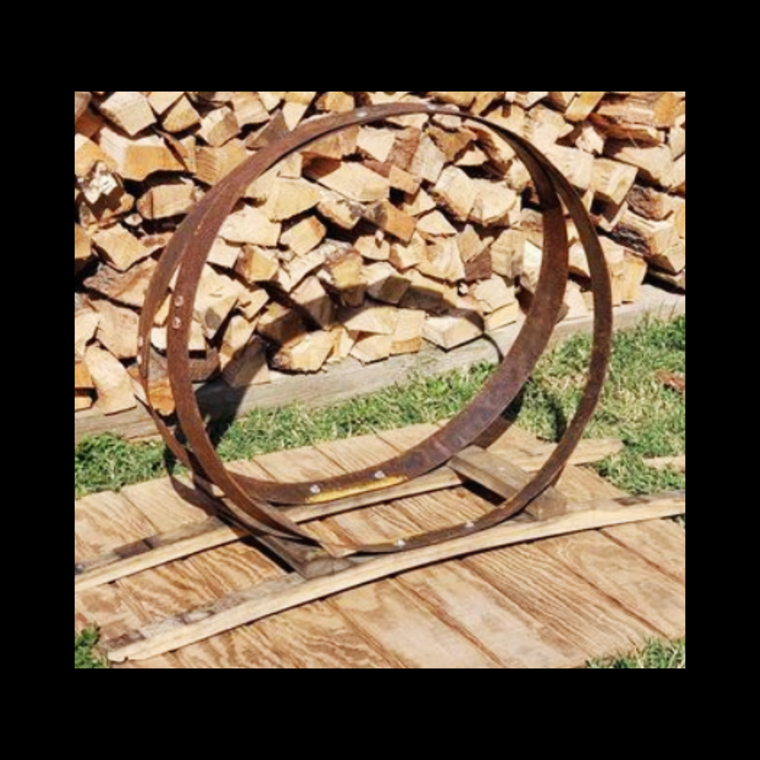 Firewood rack fashioned from two reclaimed barrel hoops and staves.