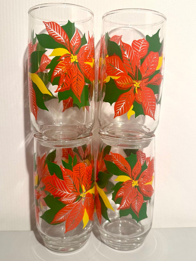 Four glass tumblers with poinsettia design on a white background