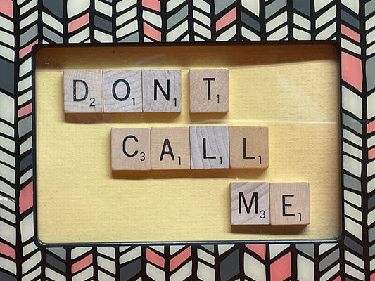 Wooden blocks with letters spelling 'DON'T CALL ME' on a decorative background