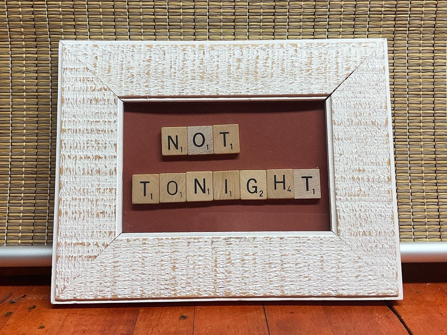 Framed artwork with 'NOT Tonight' spelled out using wooden letters on a rusty red background.