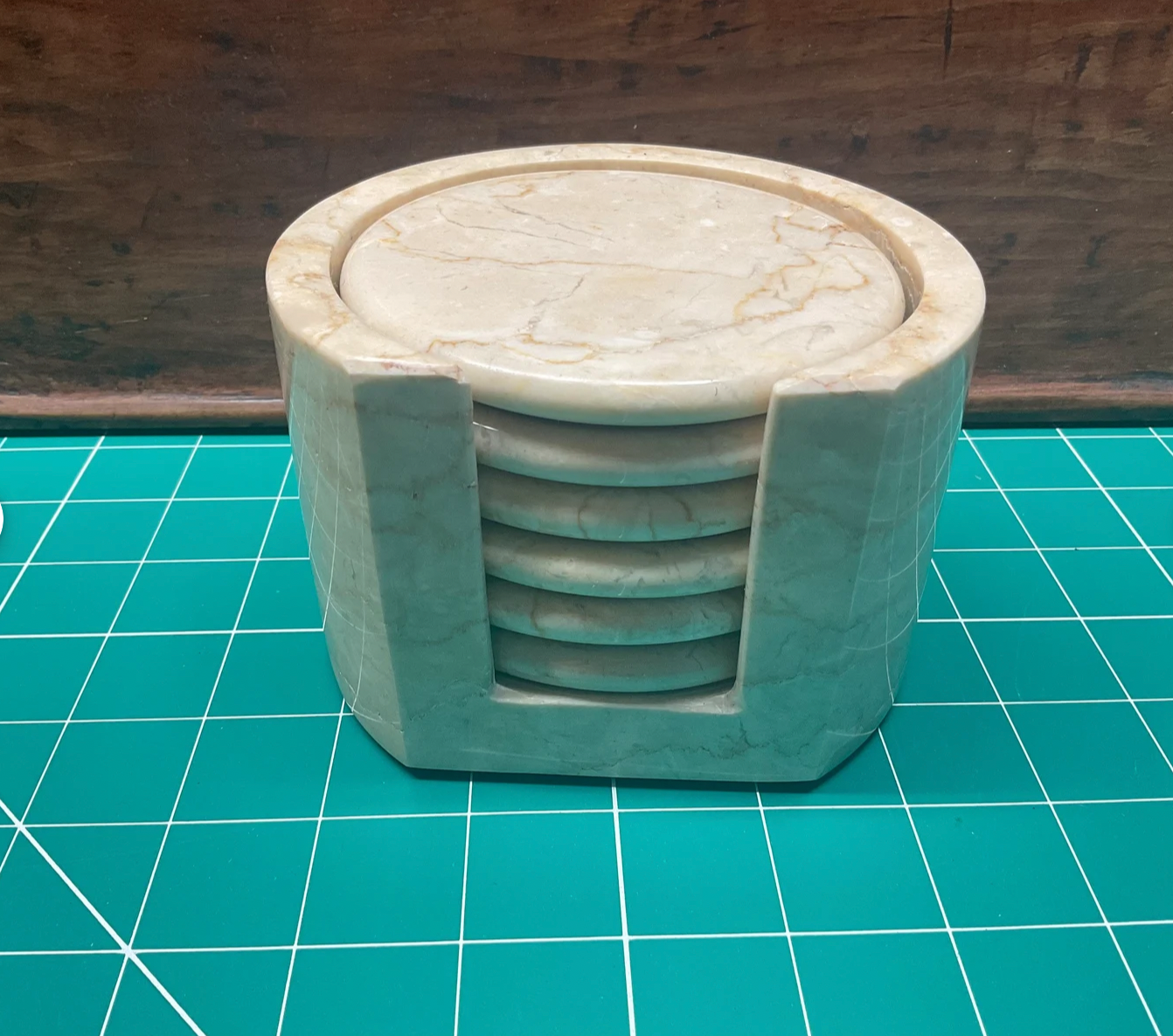 Set of marble coasters in a holder on a green grid surface