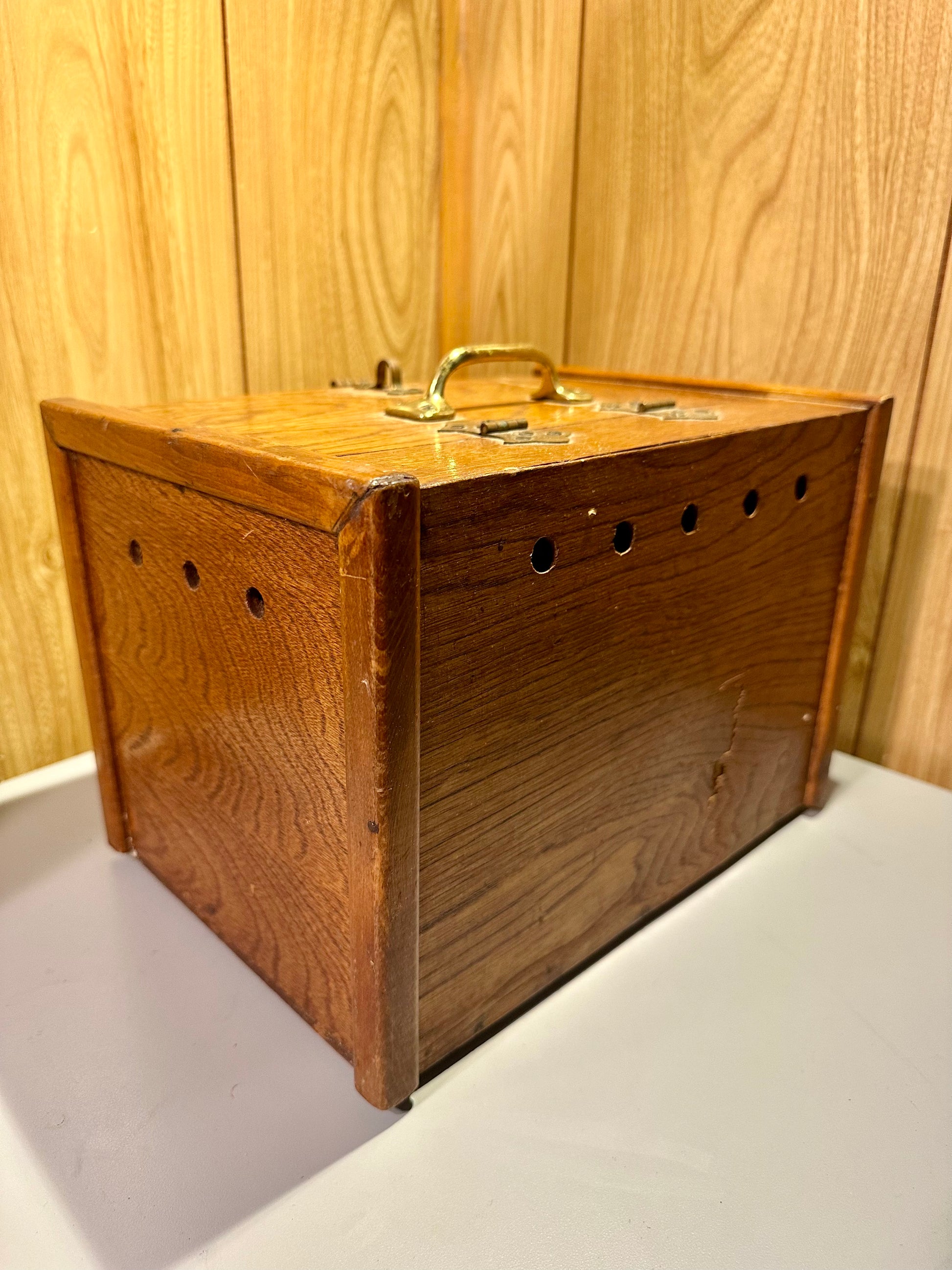 Wooden box with a handle on a surface against a wooden panel background