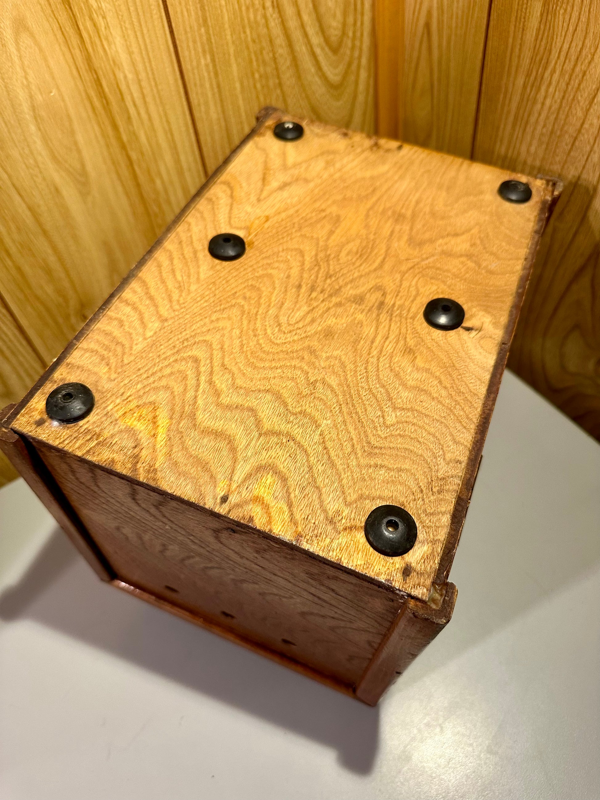 Wooden box with a textured surface and six black feet on a wooden background