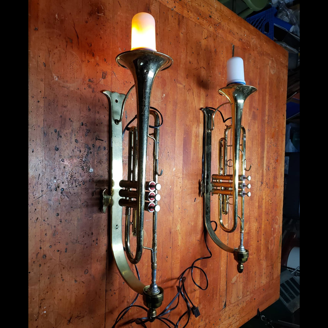 Pair of trumpets mounted as brass wall sconces with flickering flame bulbs, made by Fox & Thistle Studio.