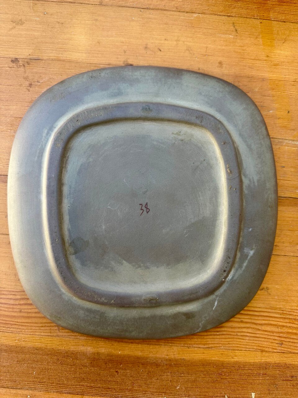 Ceramic ashtray with the number 38 on a wooden surface