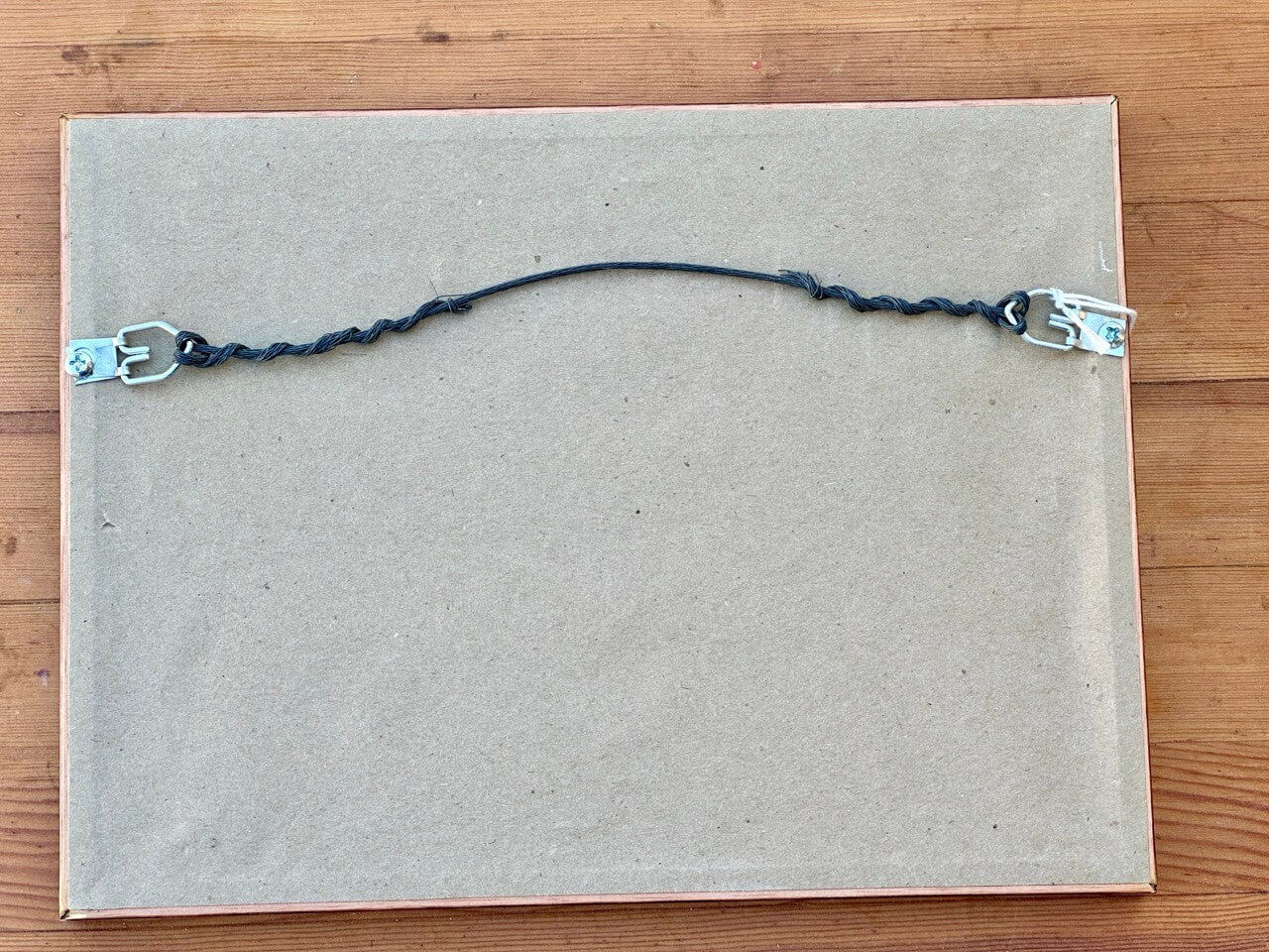 Dust cover of a framed picture with picture wire.