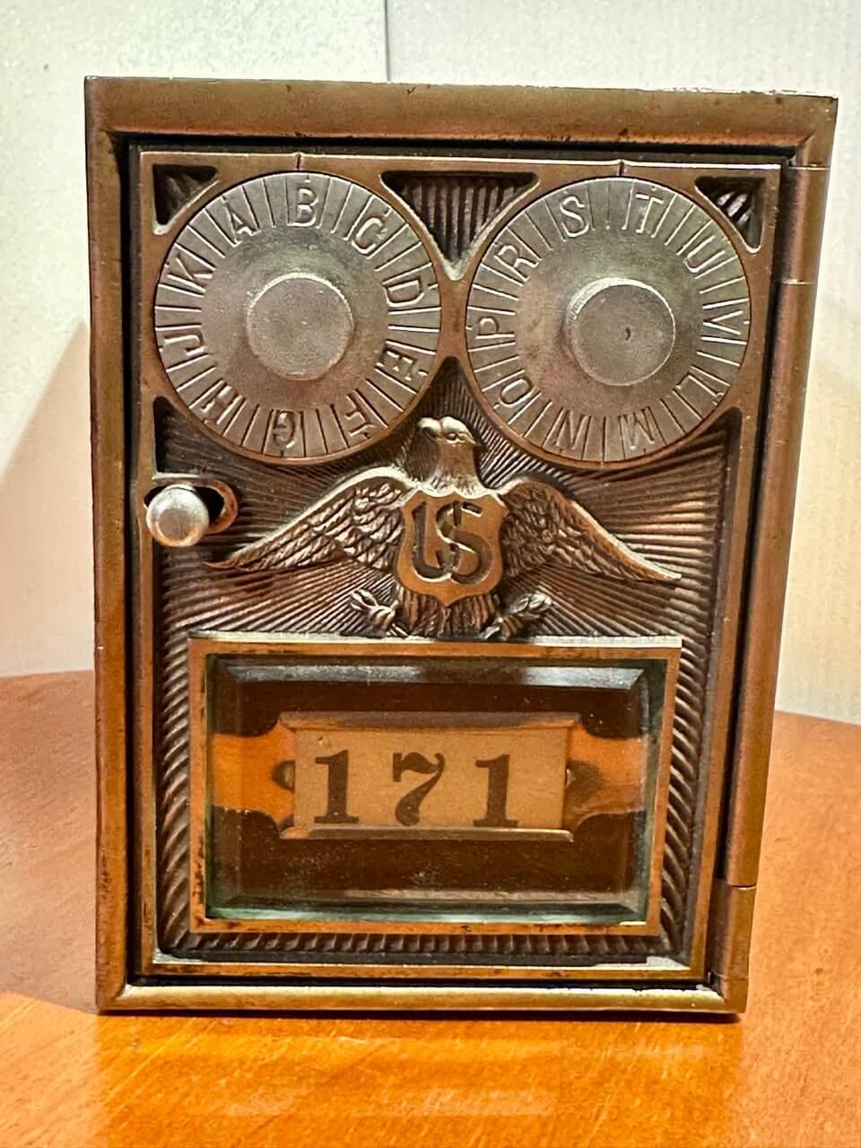 Decorative metal box with engraved design and number '171' on a wooden surface.