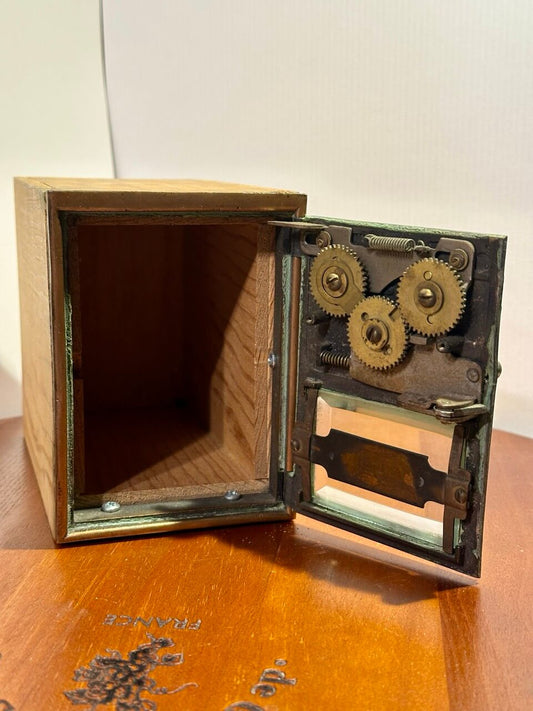 Wooden box with an open lid revealing mechanical gears inside.