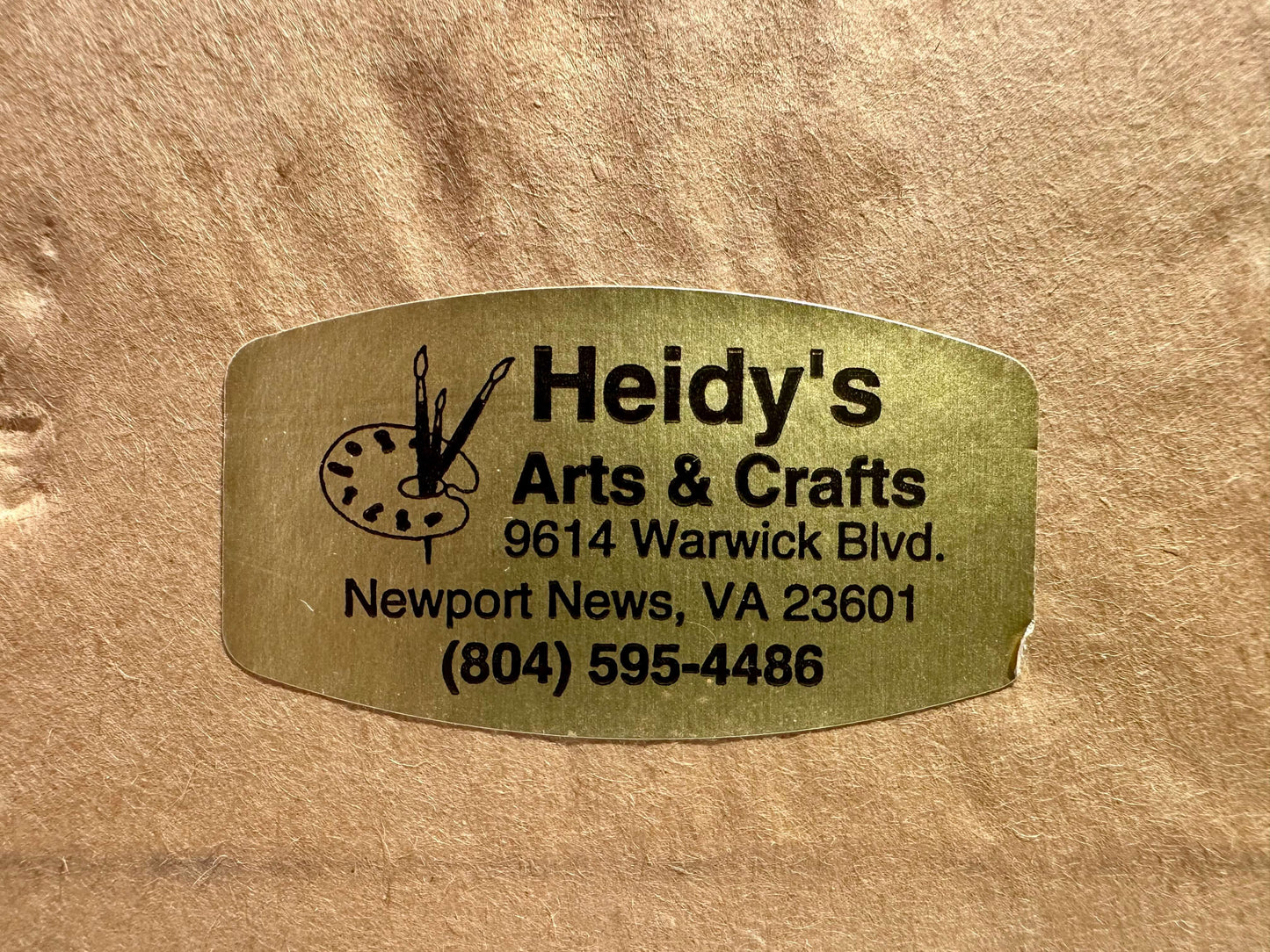 Metallic gold label with 'Heidy's Arts & Crafts' text and contact information on a brown background