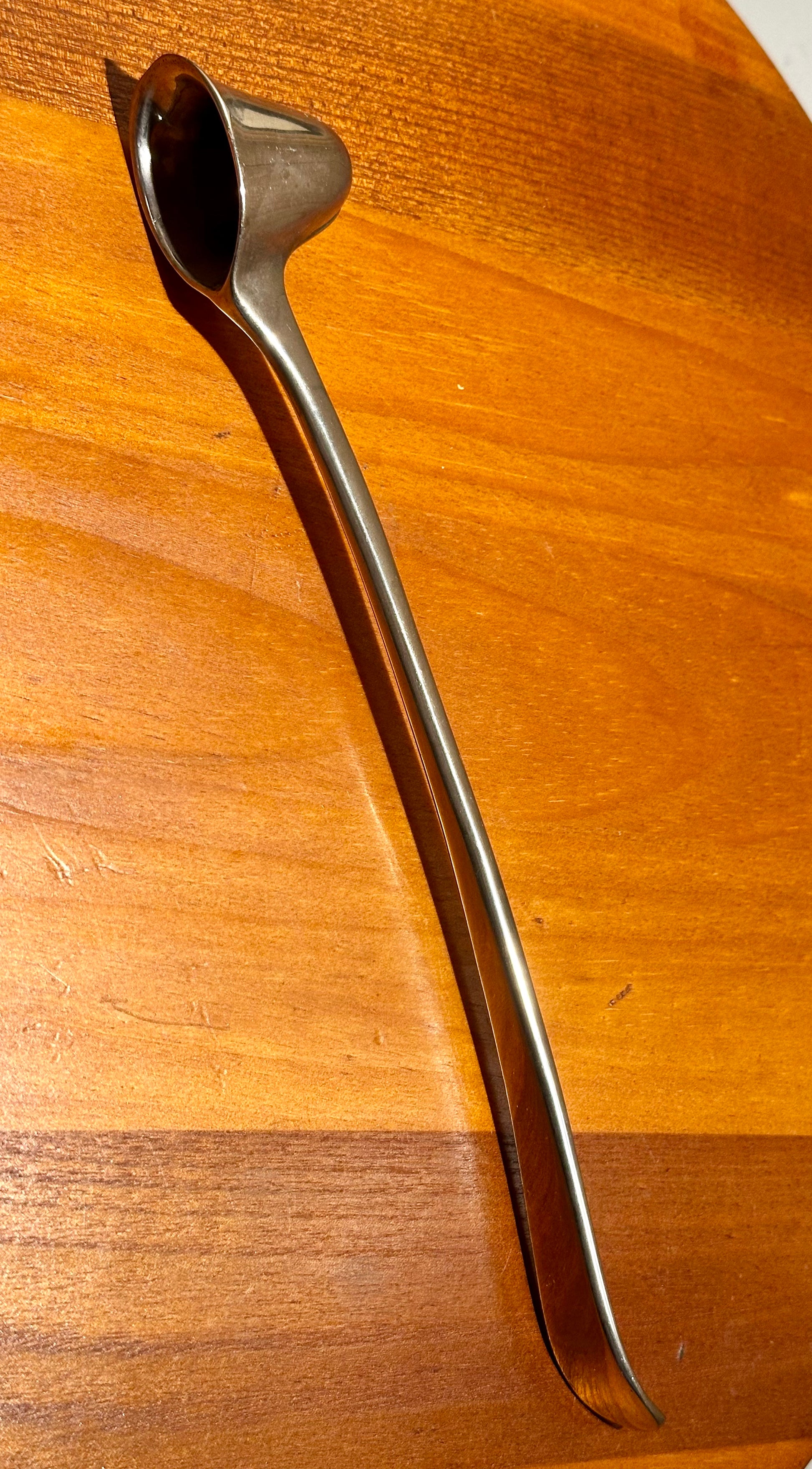 Metallic candle snuffer on a wooden surface