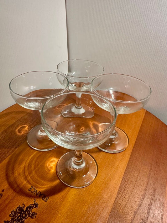 Four champagne glasses arranged on a wooden surface.