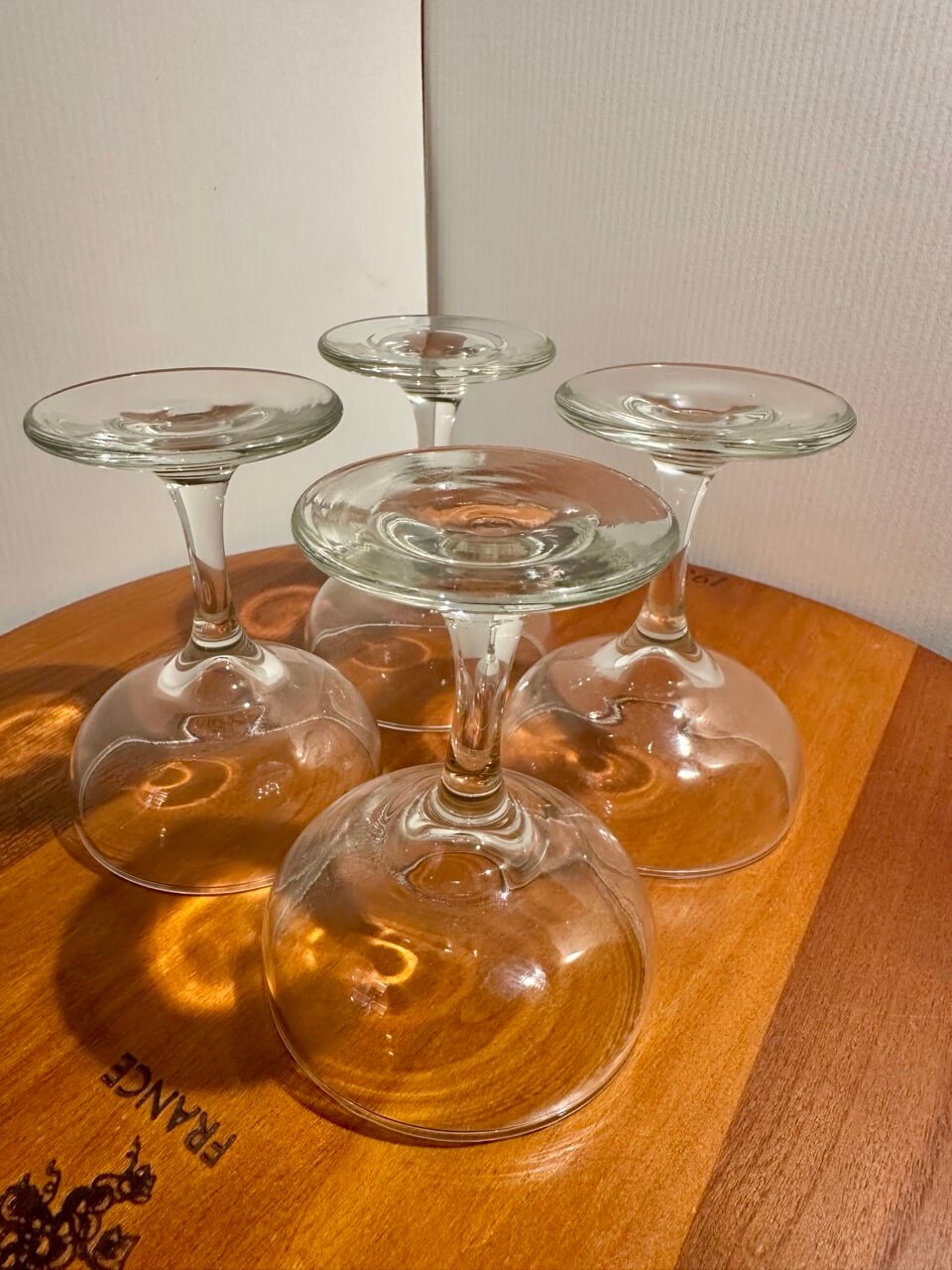 Four coupe champagne glasses upside down on a wooden surface.